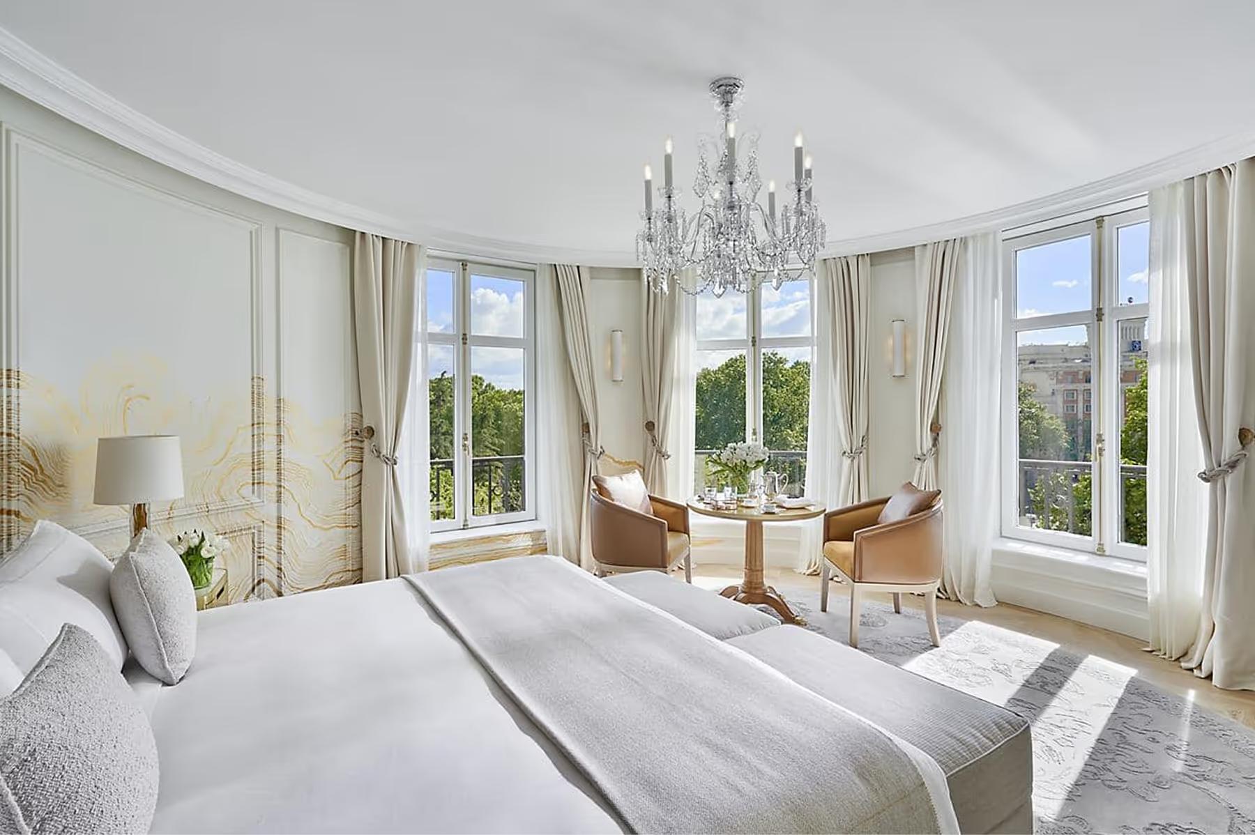 Bedroom with white bedding, tall windows, and brass table lamps
