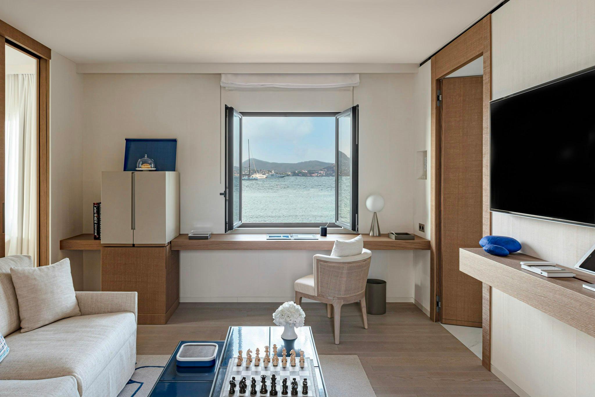 Contemporary suite with desk, white bed, and sea-view opening