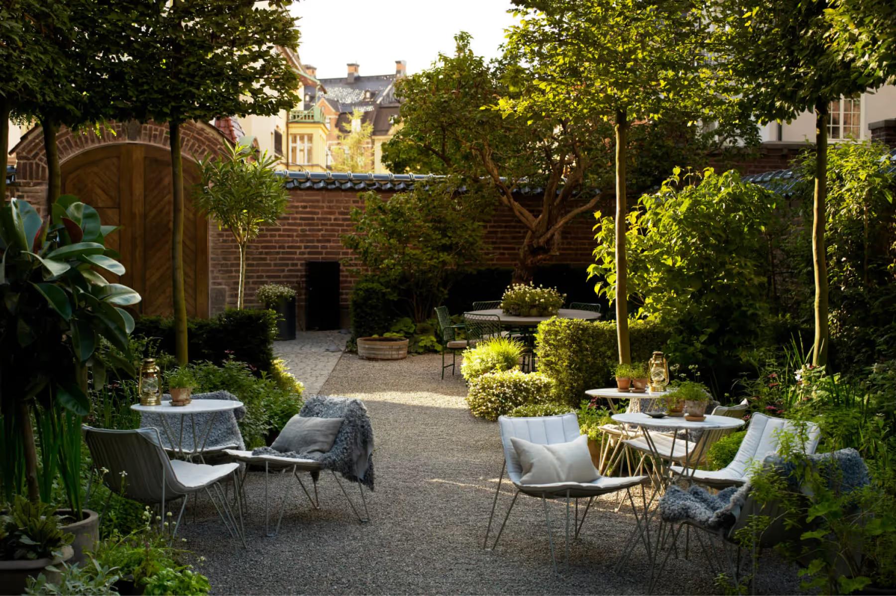 Ett Hem: an outdoor garden seating area with white lounge chairs under trees