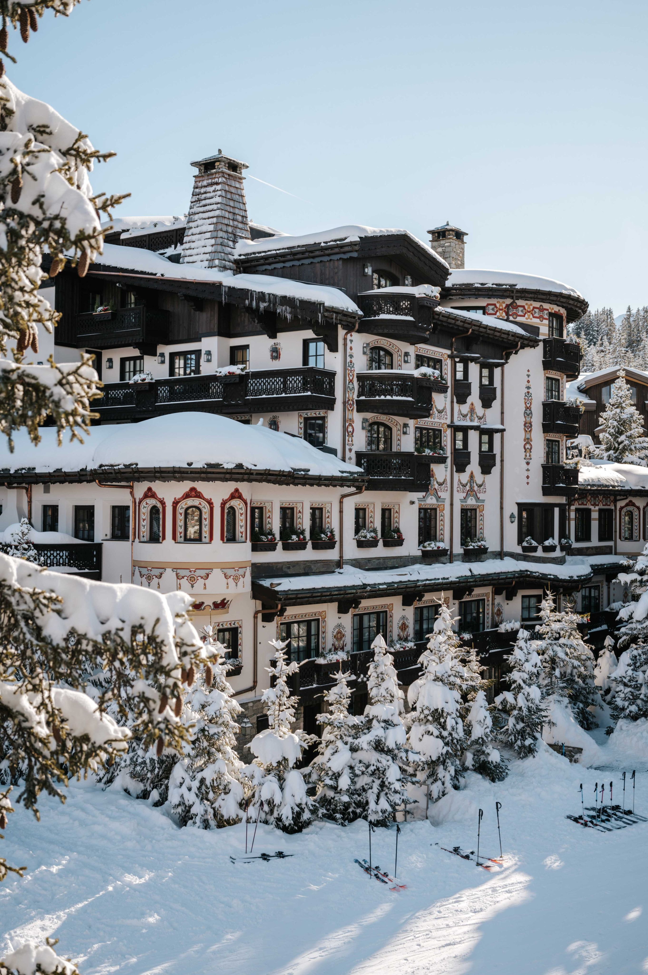 The painted, turreted façade of Les Airelles behind snow-covered firs