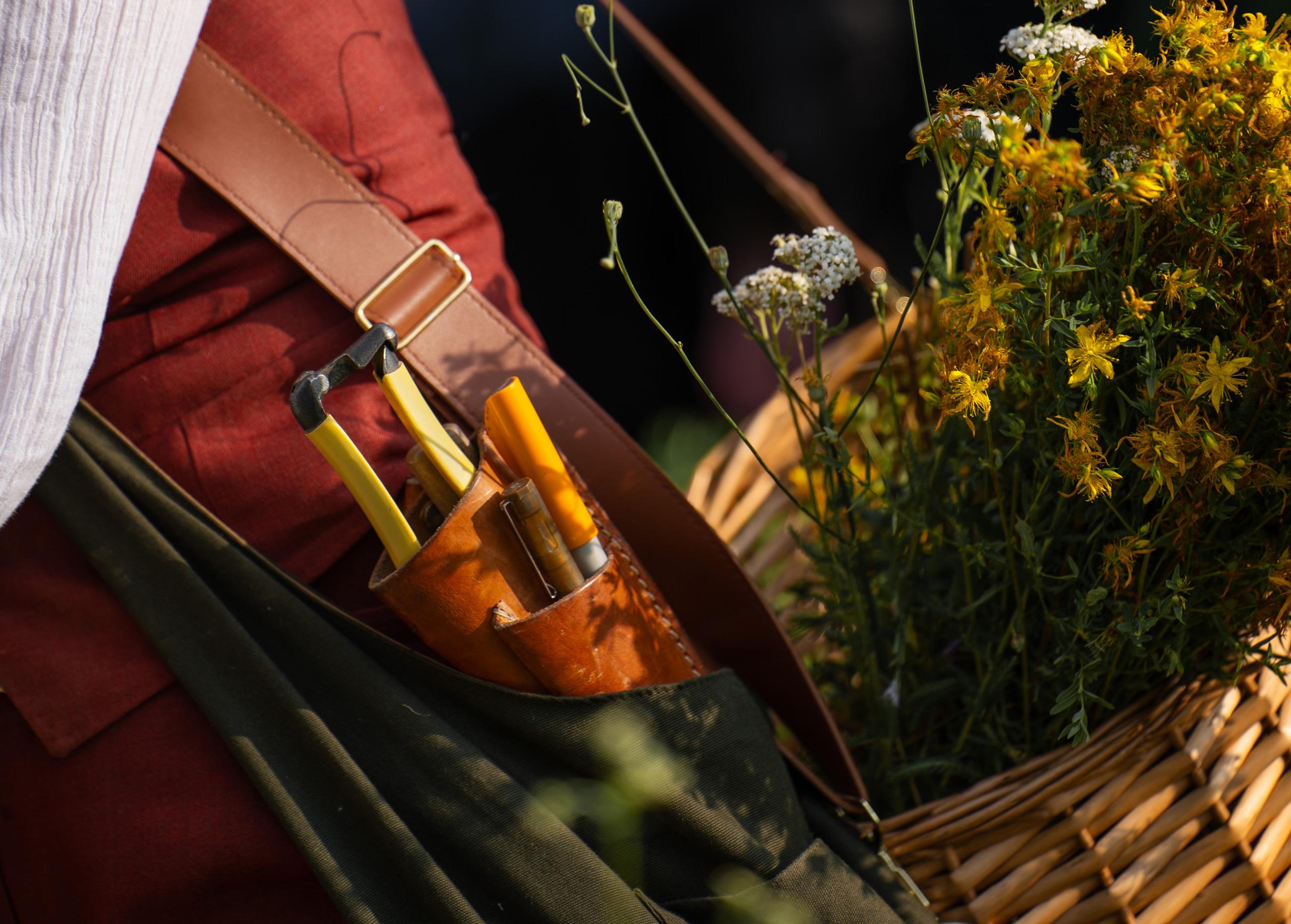 Castello di Reschio: a close up of leather tool pouches and pruning shears against wildflowers and a canvas apron