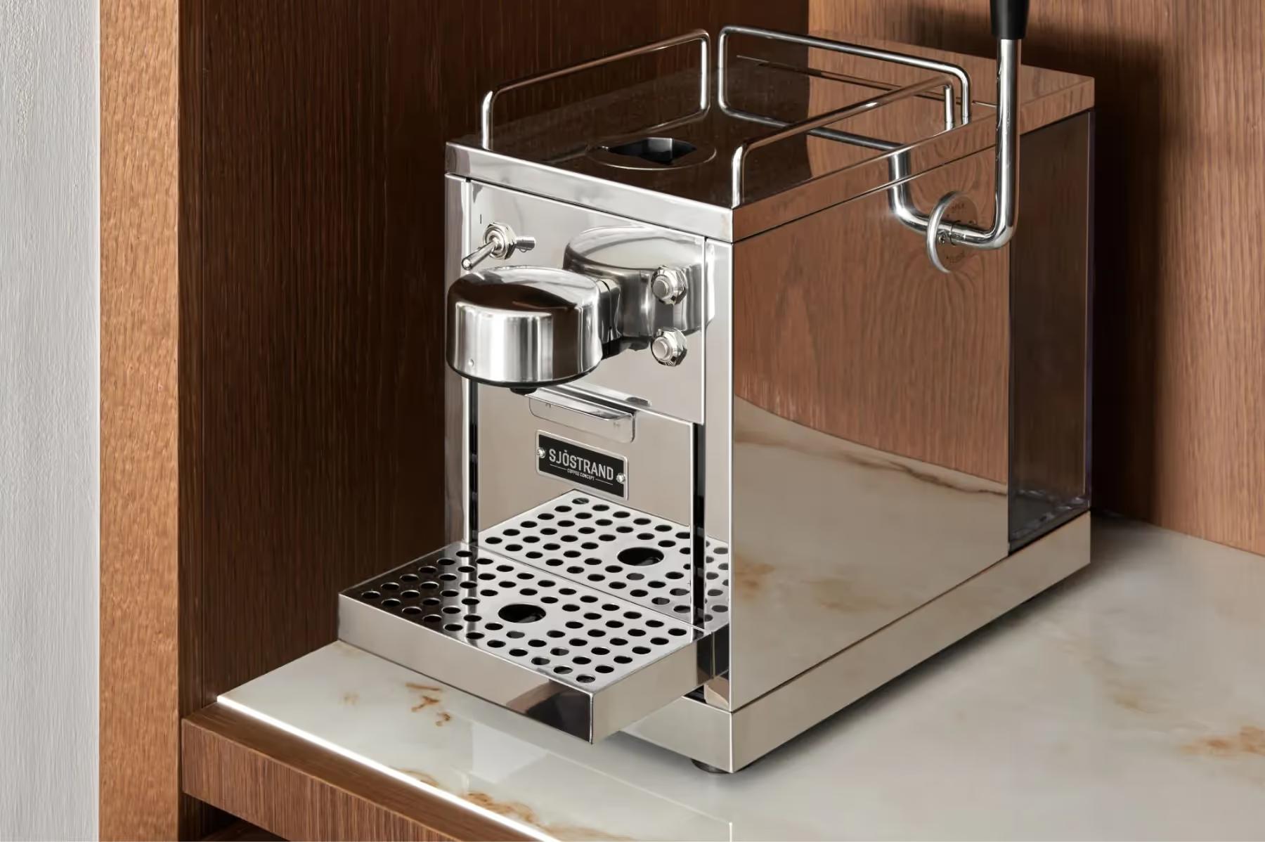 Espresso machine built into wood cabinetry in room amenities station