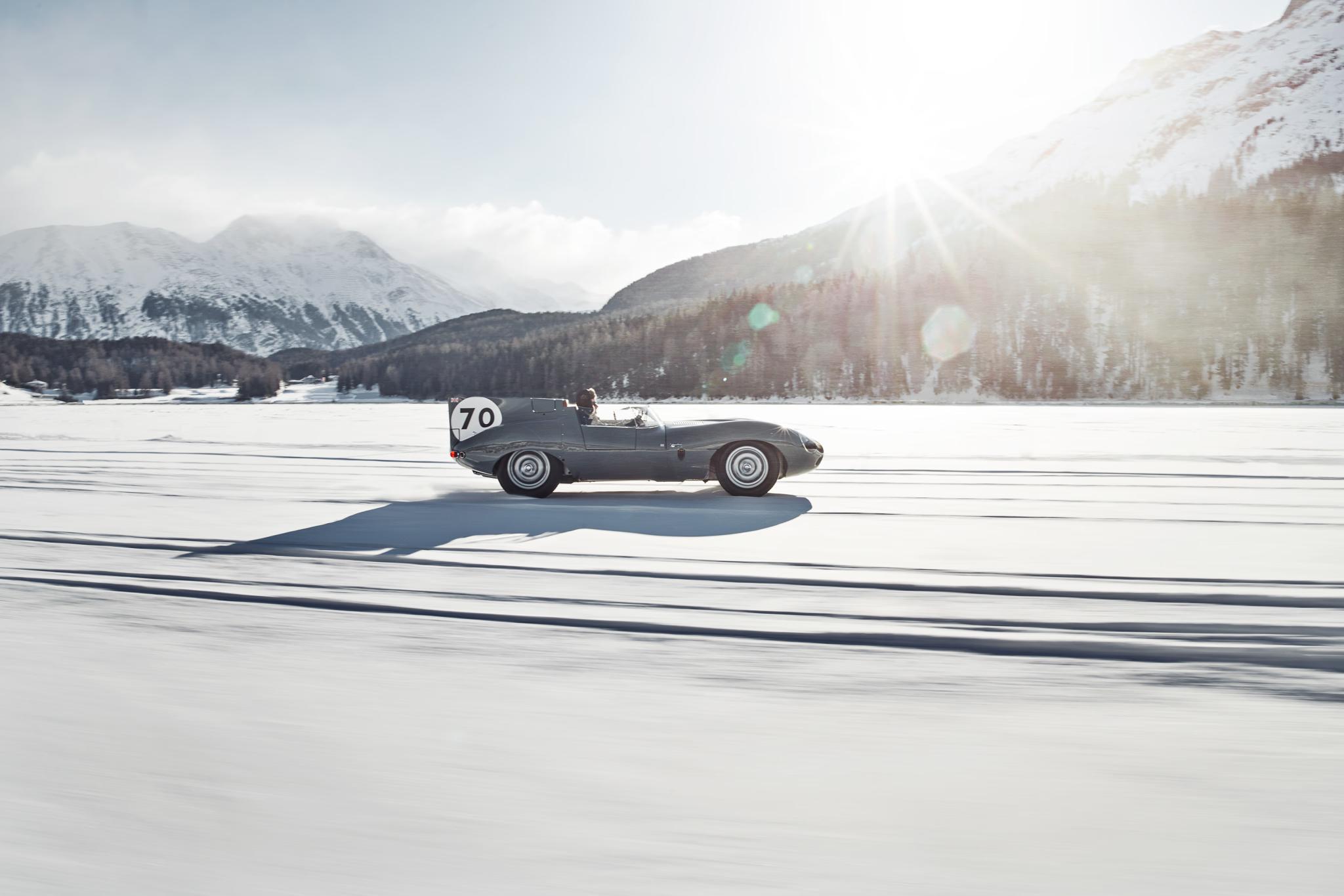 Suvretta House: a vintage car racing on a snowy alpine lake with forested mountains beyond