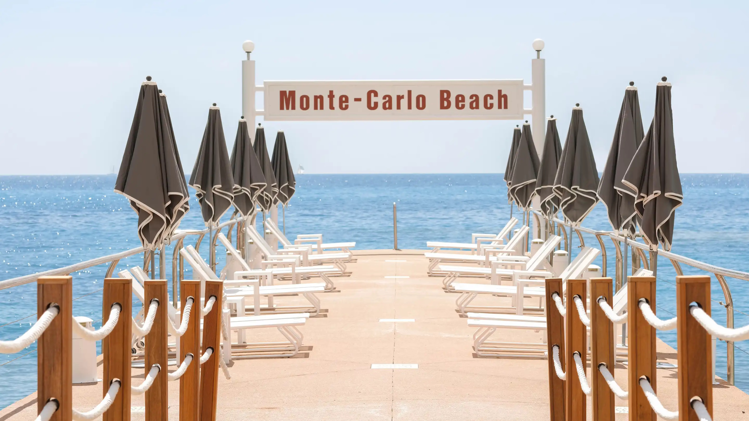 Hôtel de Paris Monte-Carlo: Monte-Carlo Beach with white lounge chairs, charcoal umbrellas, rope railings, and sea views