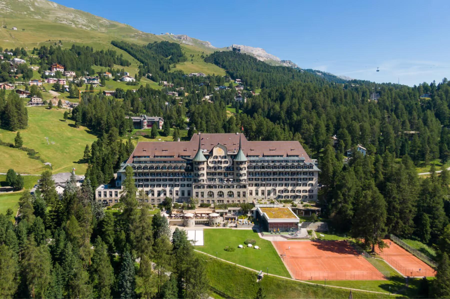 Suvretta House: the hotel surrounded by meadows and forest with larch and pine trees across rolling terrain