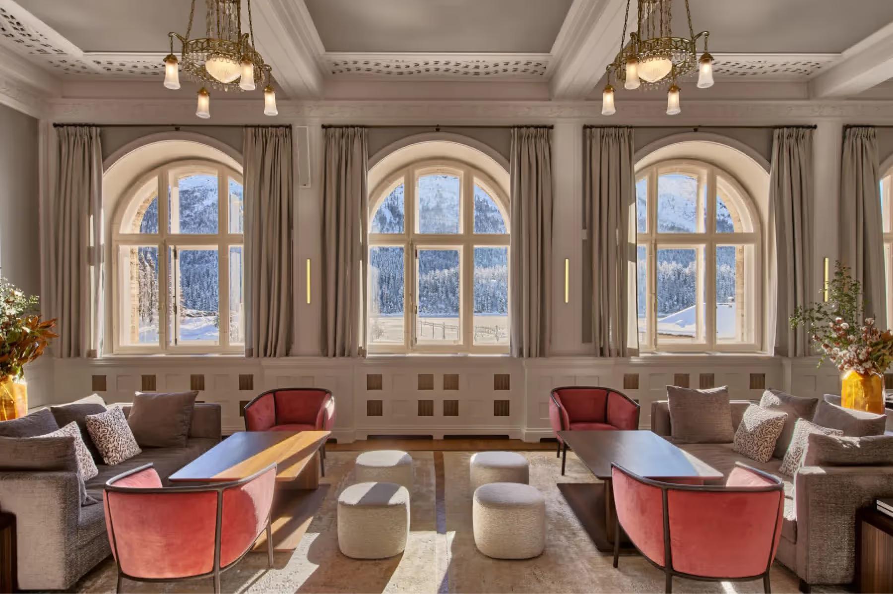 Elegant lounge with arched windows, coral seating, and neutral furnishings in cream tones