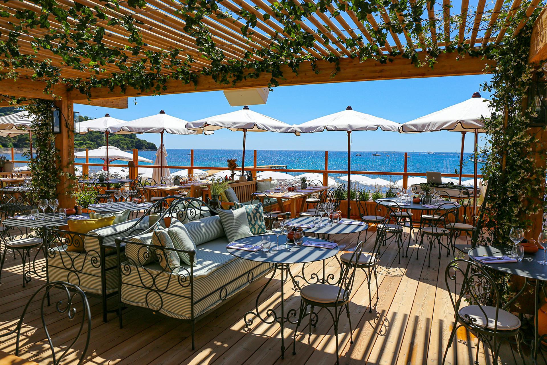 Château de La Messardière: waterfront dining terrace with latticed shade structure and panoramic bay views