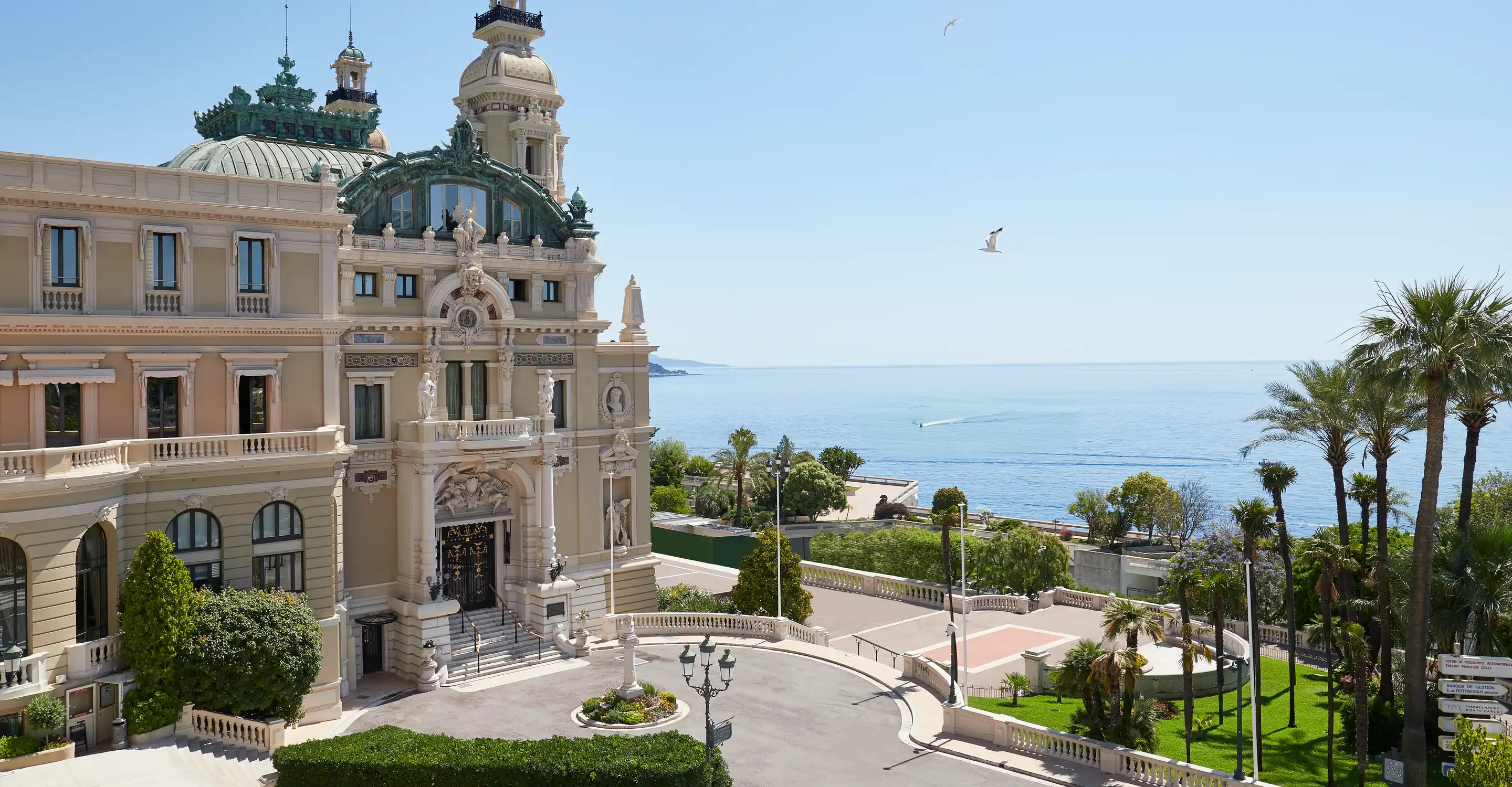 Beige palazzo facade with towers overlooking the Mediterranean and palm trees