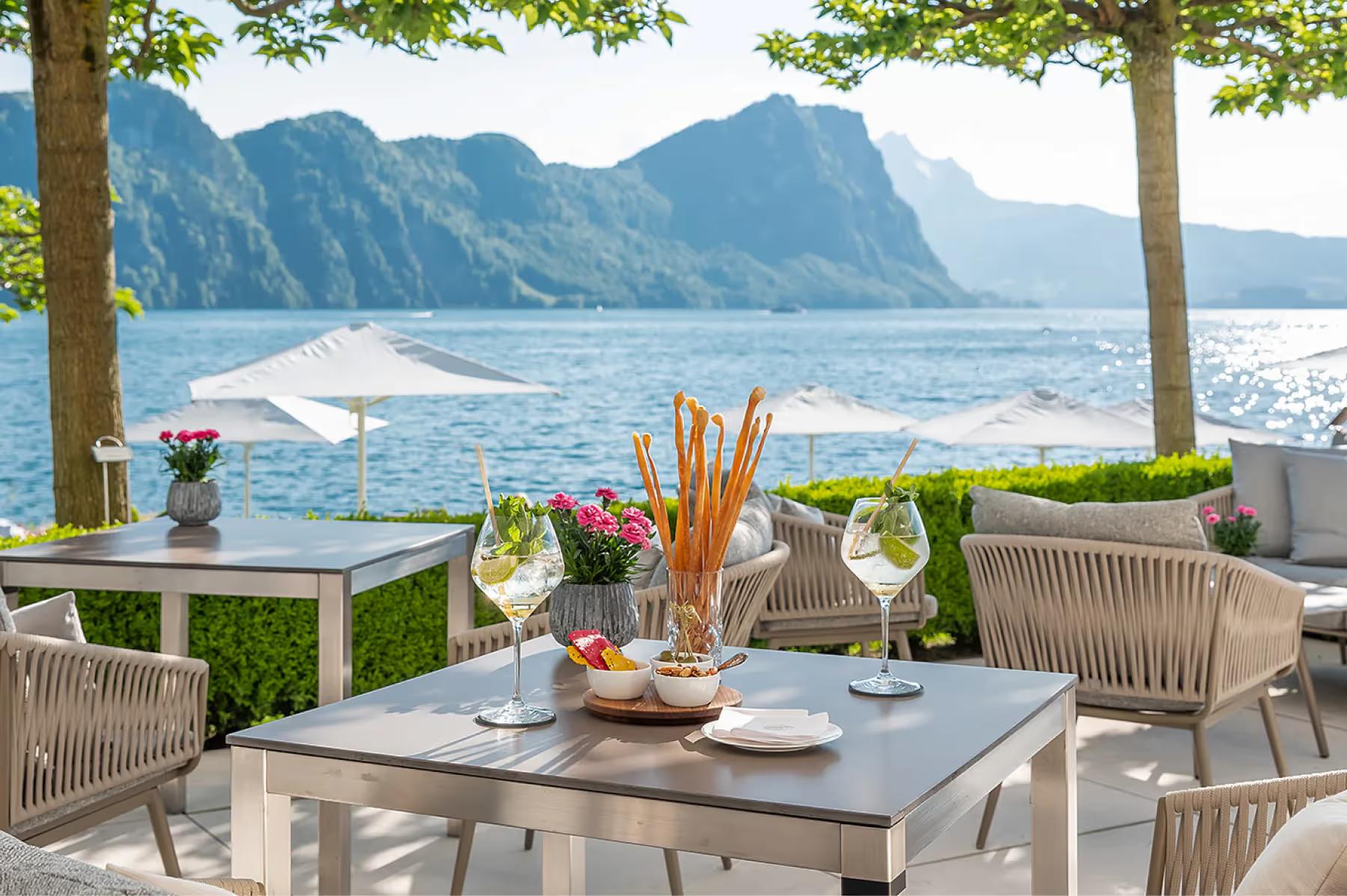 Park Hotel Vitznau: outdoor terrace with mountain views, set tables framed by trees