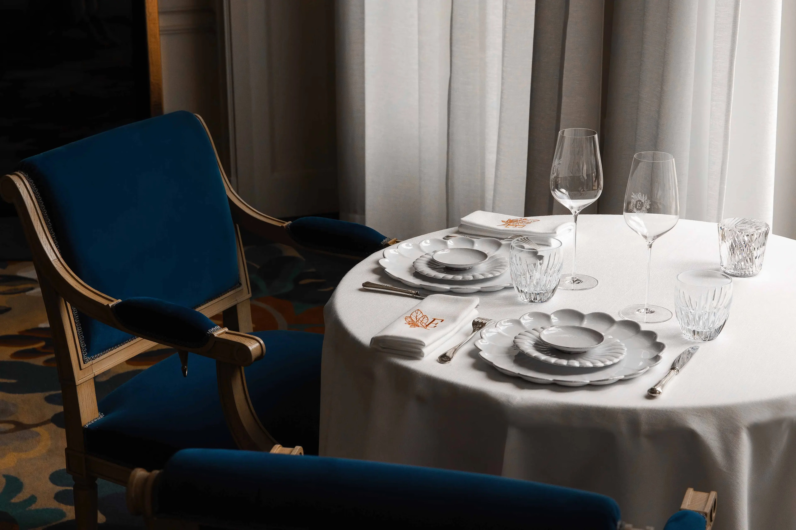 Ritz Paris: a place setting with white linens, polished flatware, and blue upholstered chair