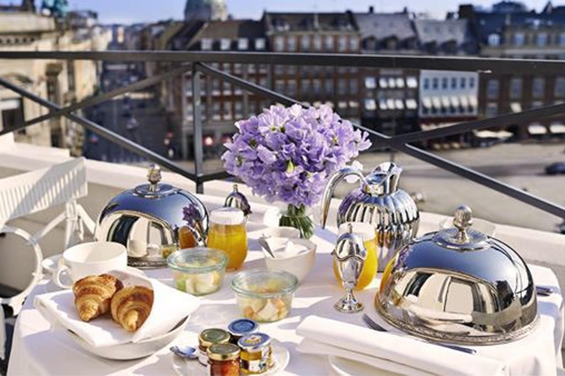 Hotel d’Angleterre: rooftop table setting with city skyline and purple floral arrangement