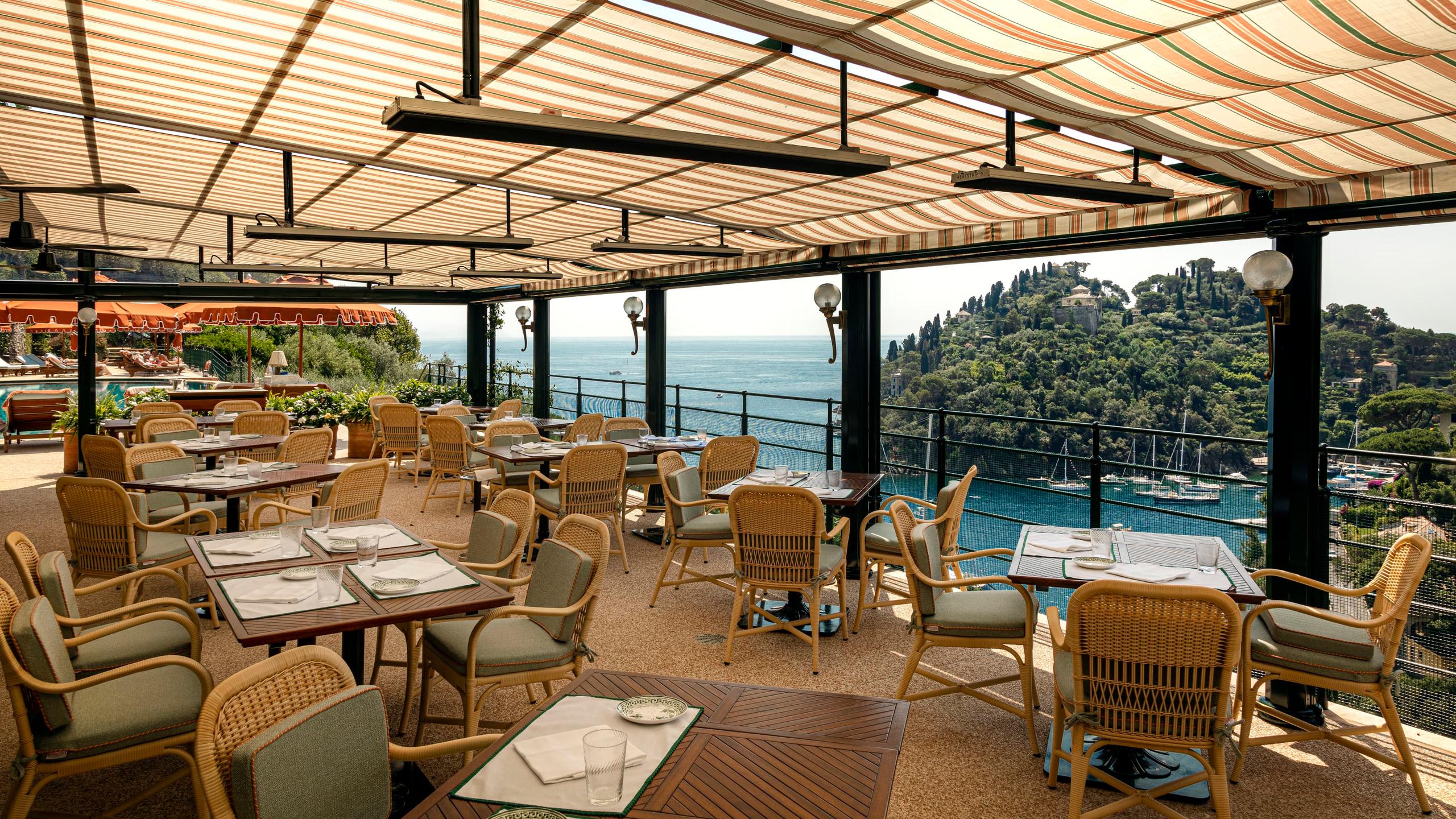 Splendido: a sheltered dining pavilion with wood furnishings and turquoise harbor below