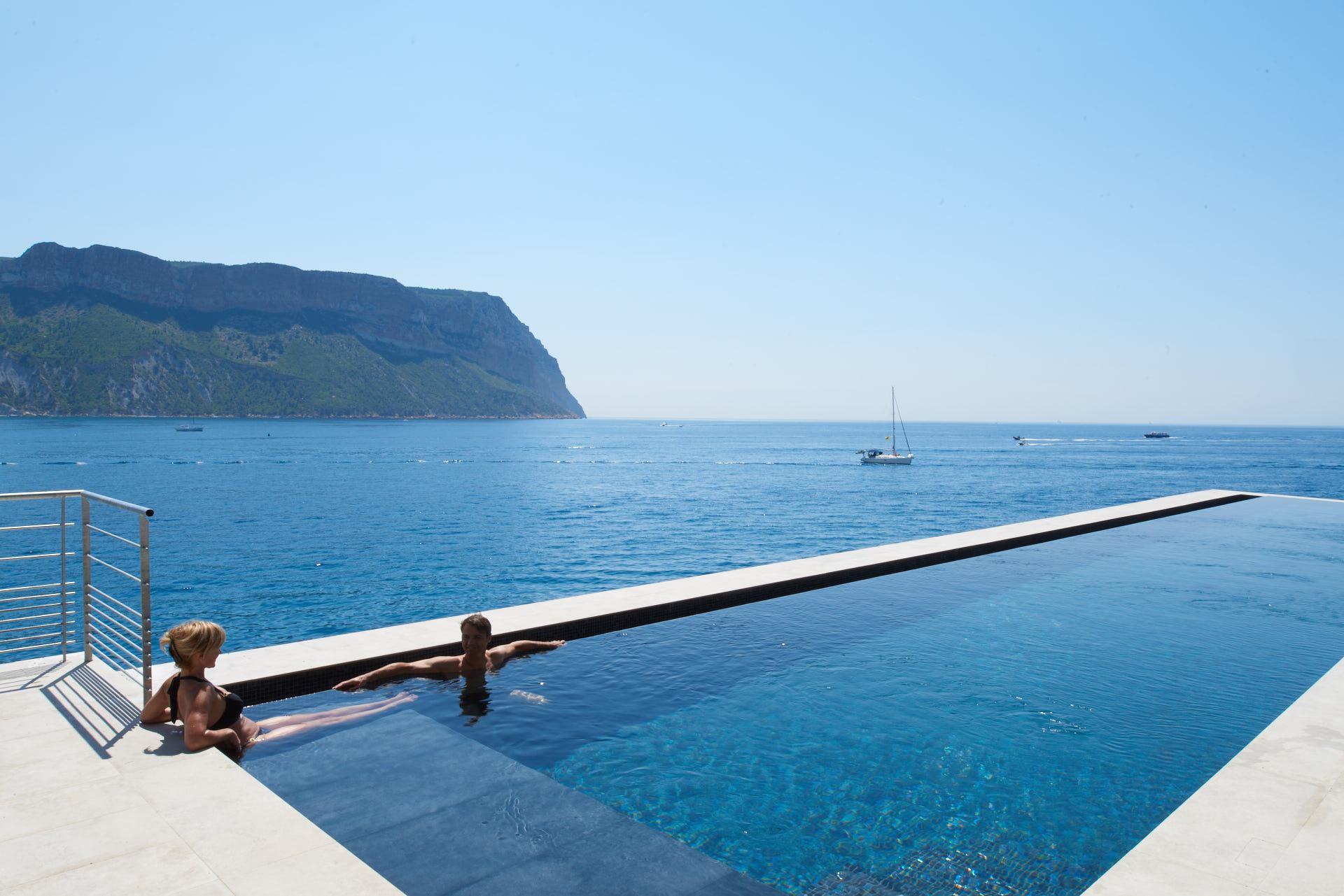 Les Roches Blanches: an infinity pool edge overlooking the sea, with the coastline and pine trees visible beyond