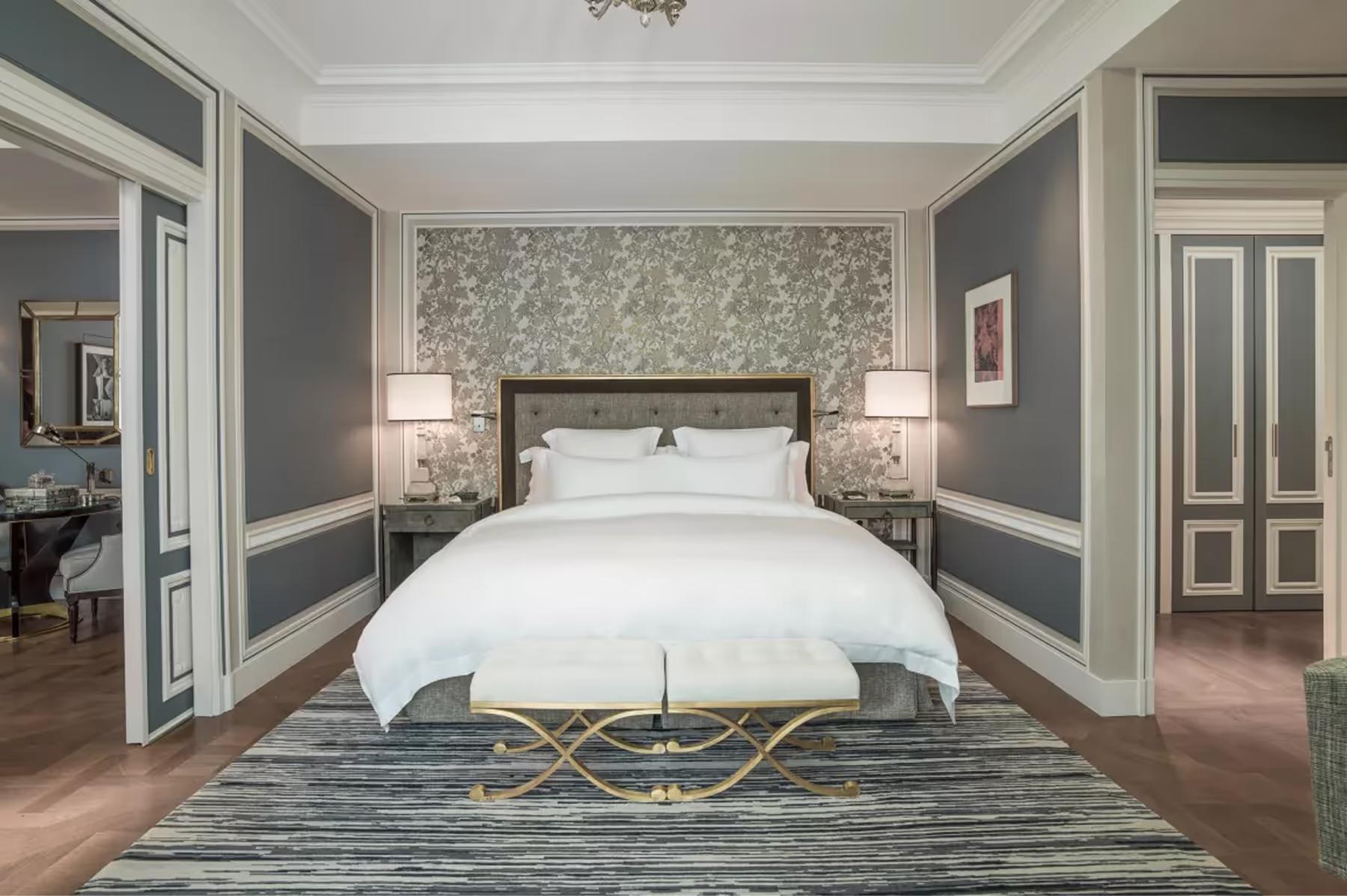 Hôtel de Crillon: suite with gray paneled walls, white bed, and coordinating furniture arrangement