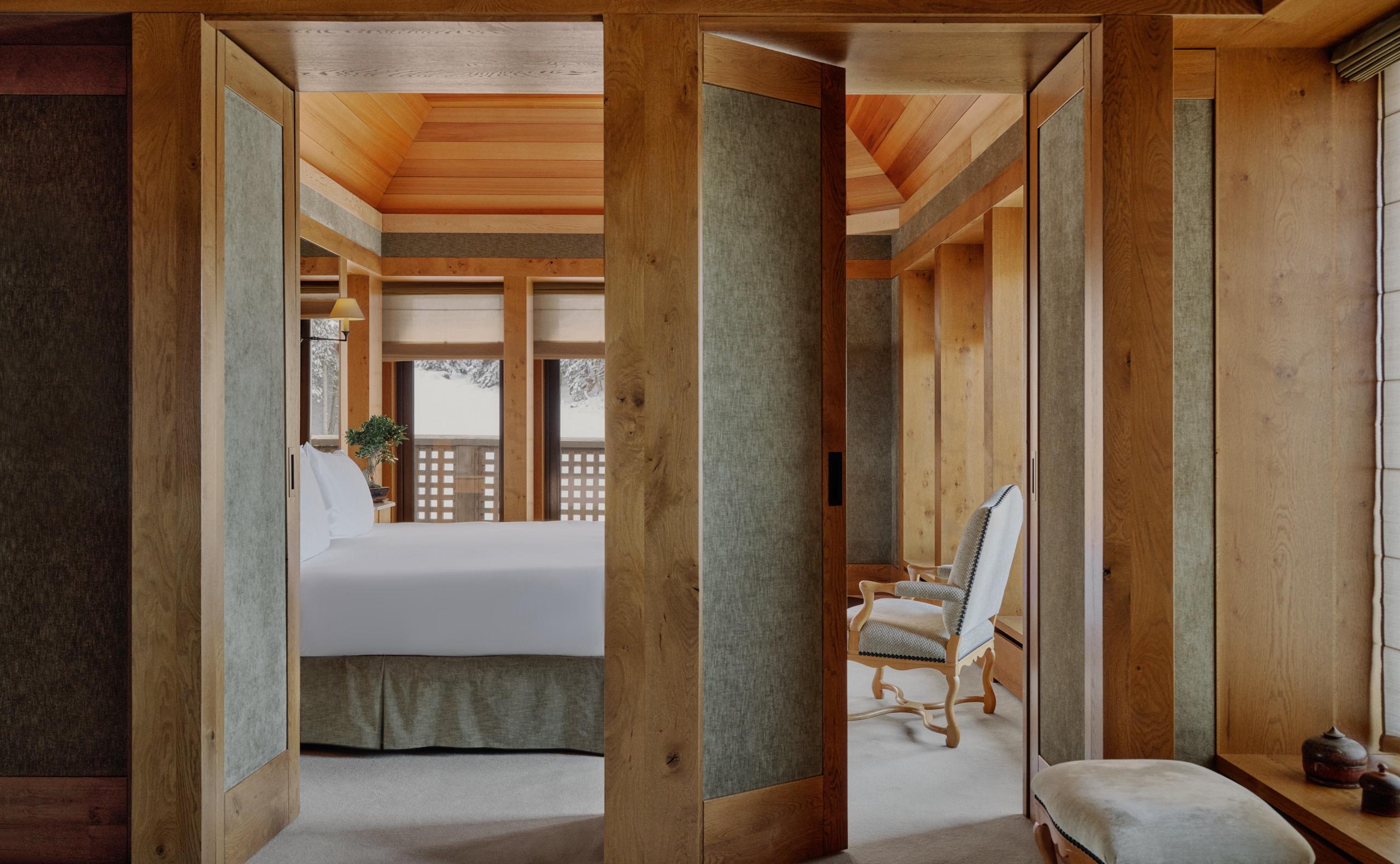 Suite viewed through open wood doors, with a bed and lattice screened window beyond