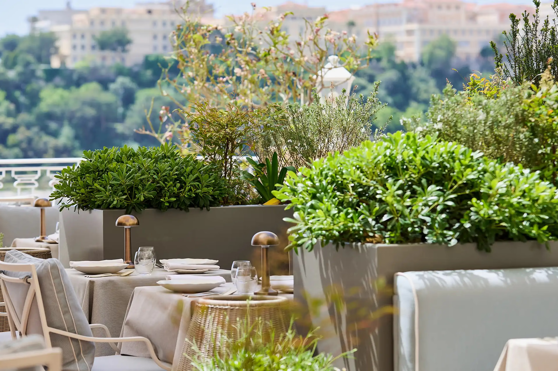 Hôtel Hermitage Monte-Carlo: outdoor dining with potted plants, stone courtyard and city views on hillside