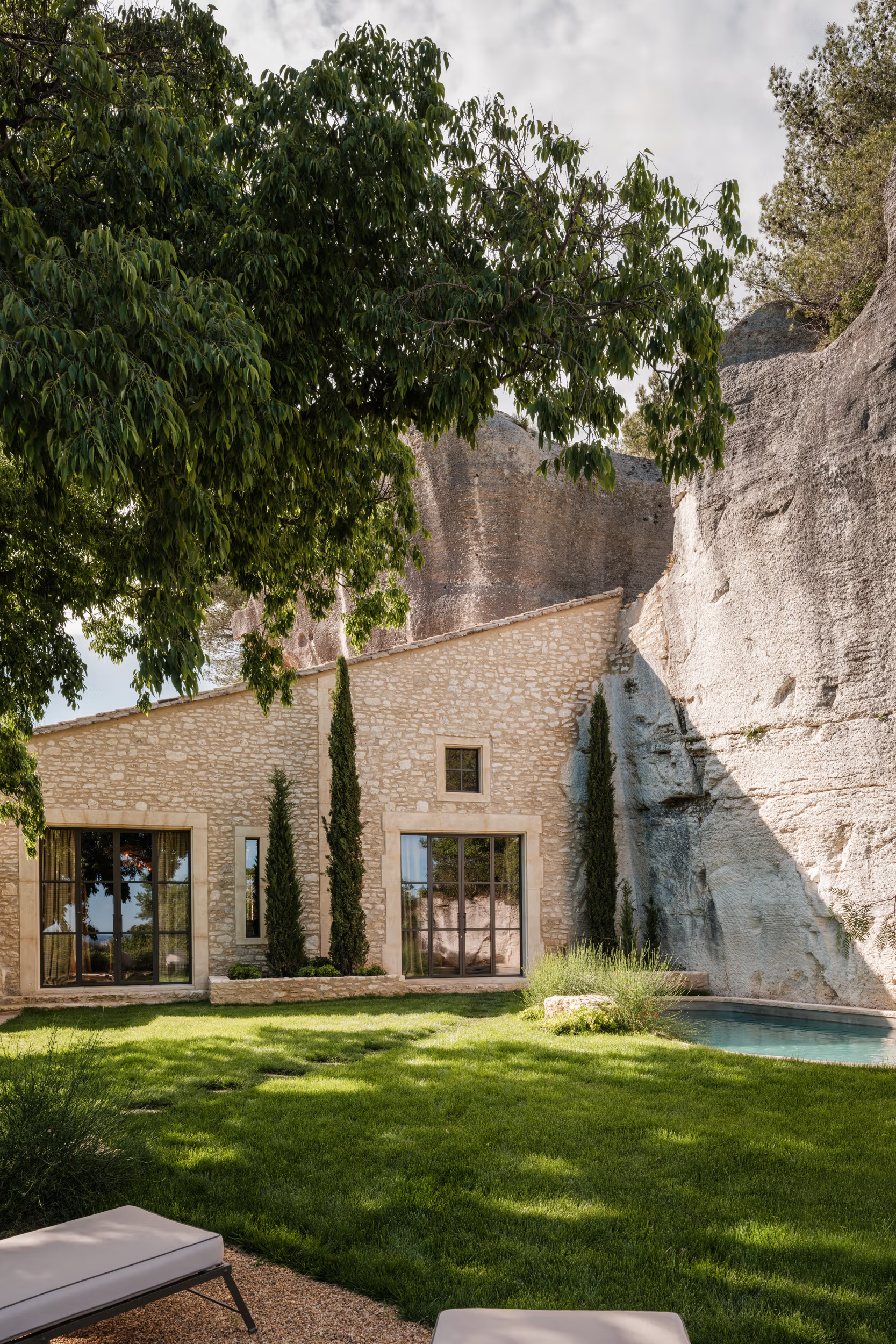 La Bergerie: shaded lounging platform with multiple white umbrellas, wooden sun beds, cypress hedge, forested slope