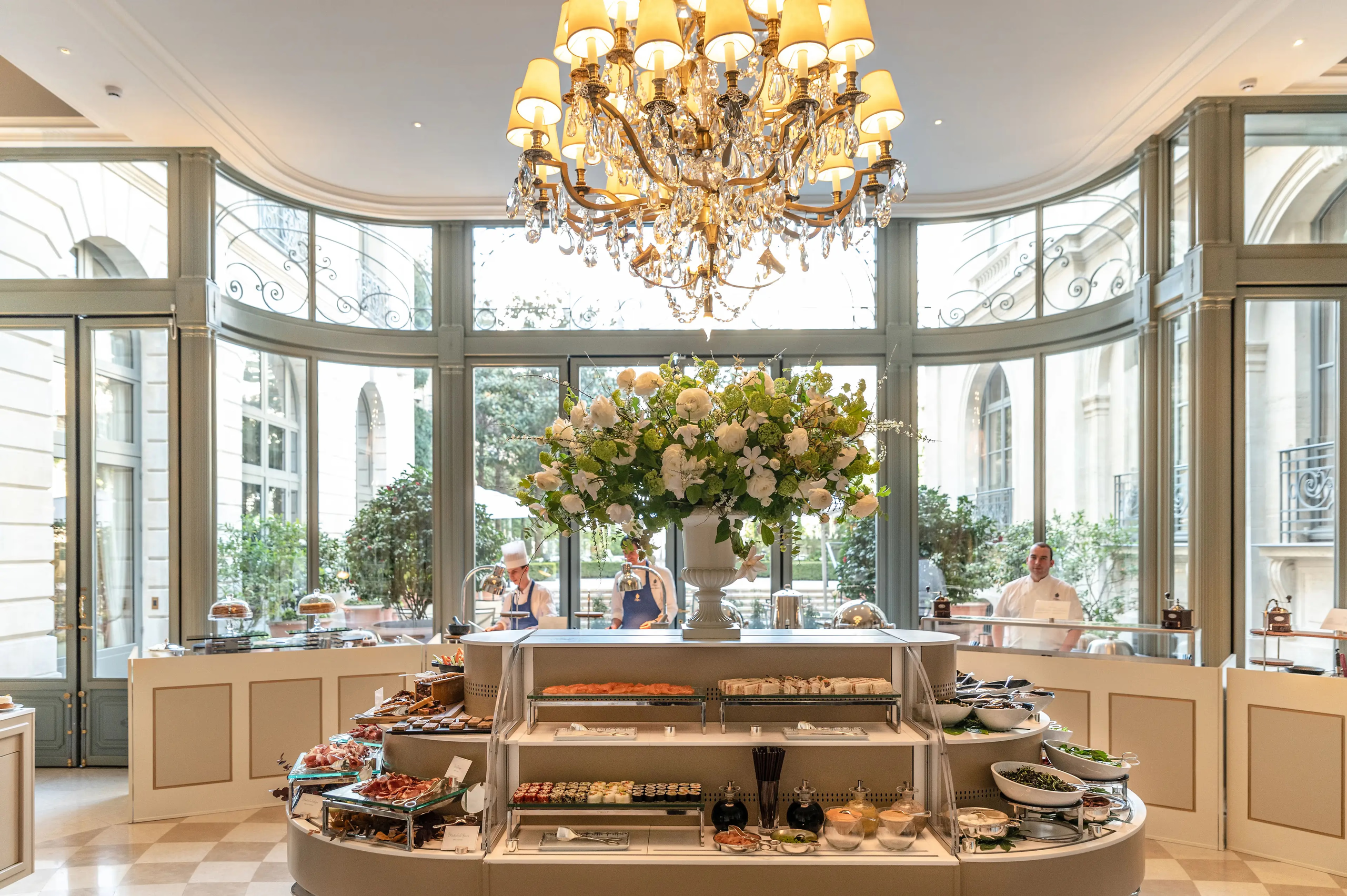A pastry display counter with flowers, gleaming surfaces, and natural light from large windows