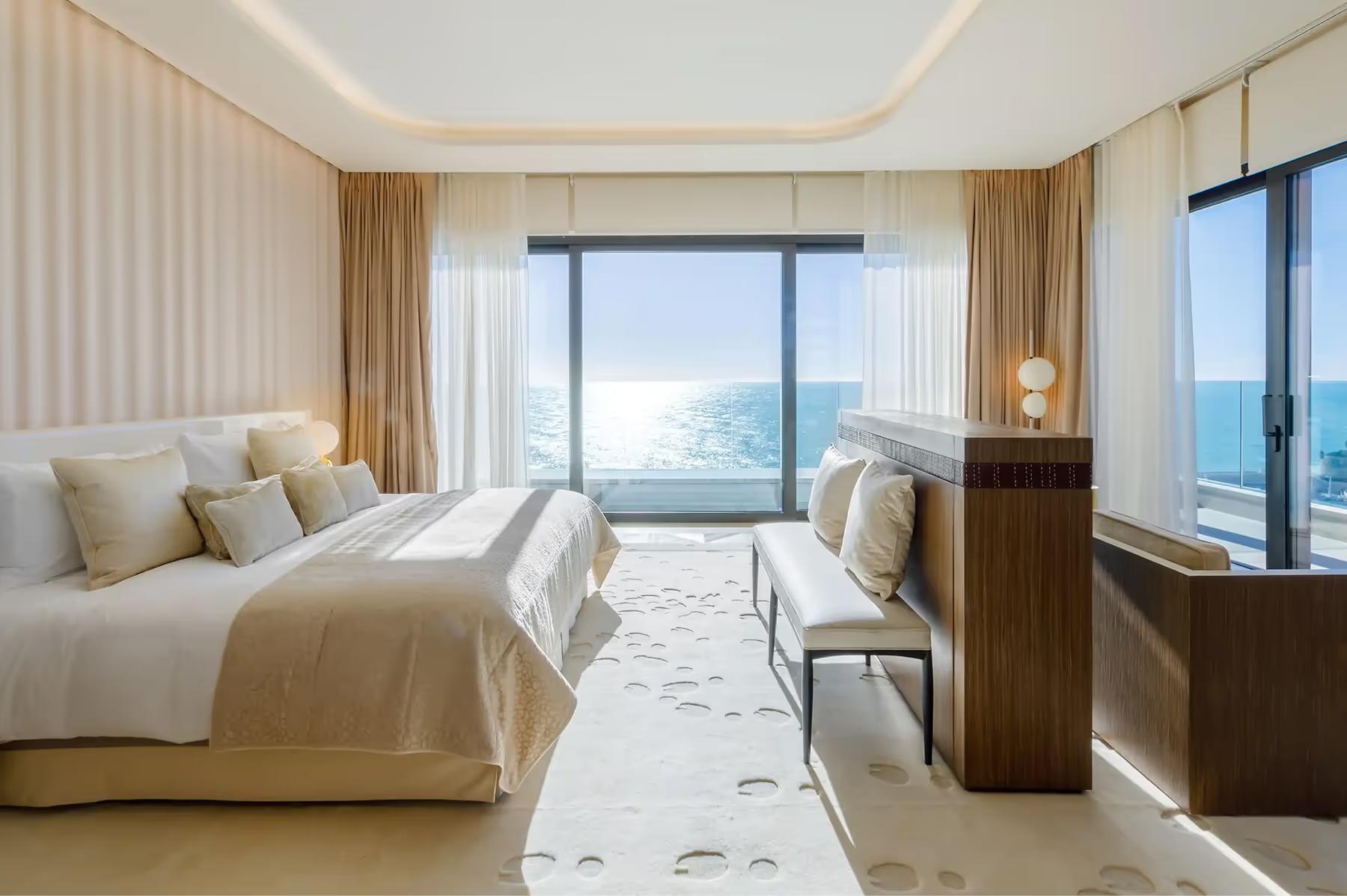 Hôtel de Paris Monte-Carlo: bedroom with white bedding, beige striped walls, open doors to sea view balcony