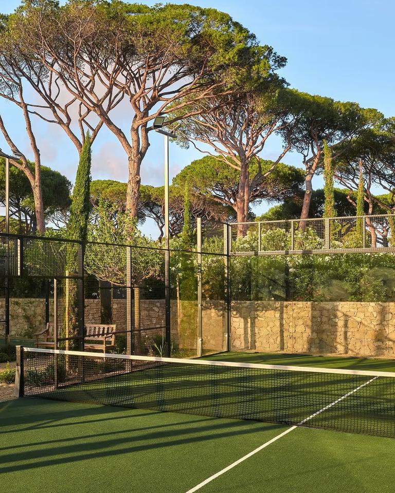 A court set into the gardens among pines and stone walls at Château de la Messardière