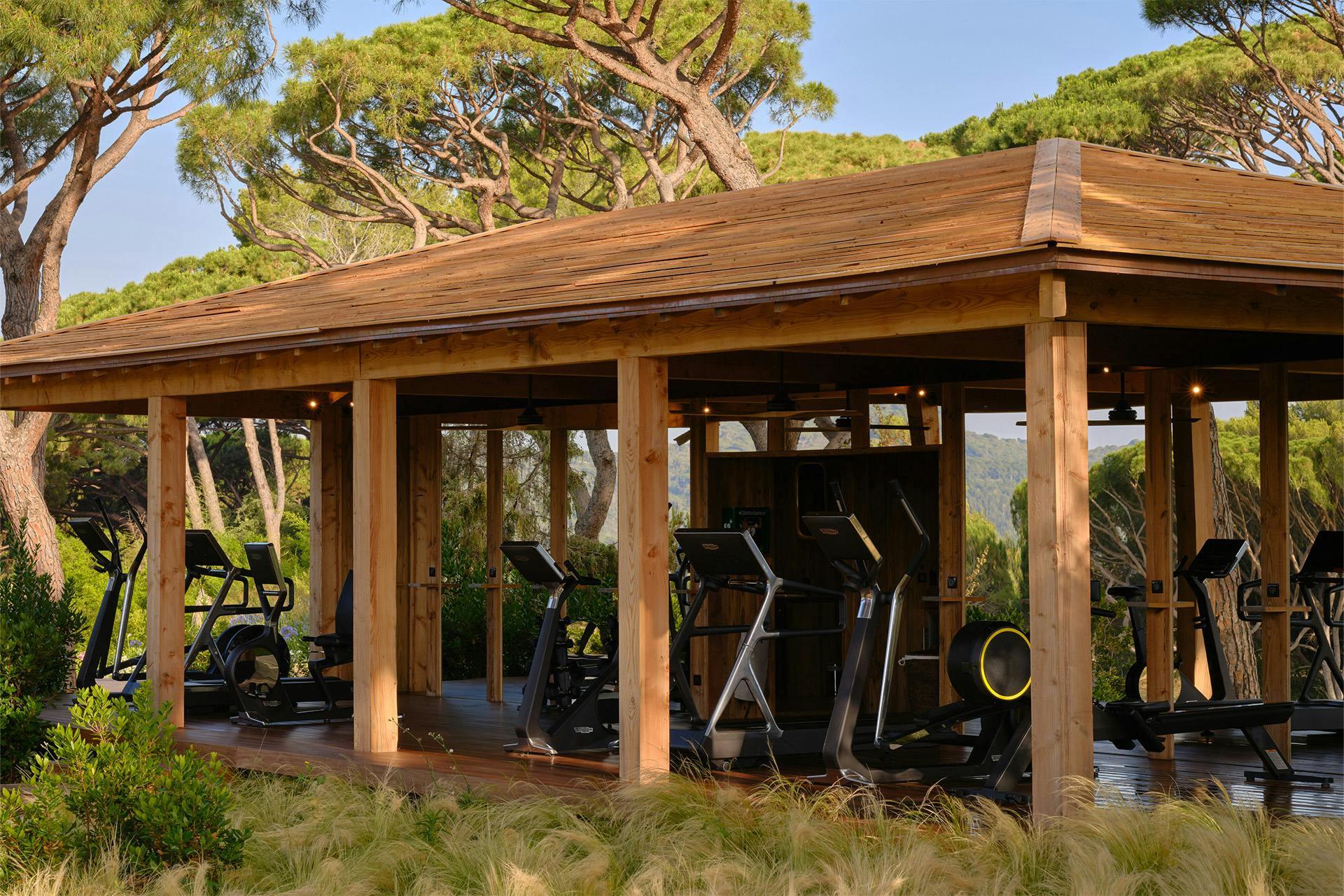 Château de La Messardière: fitness pavilion with wooden frame and equipment set in natural landscape