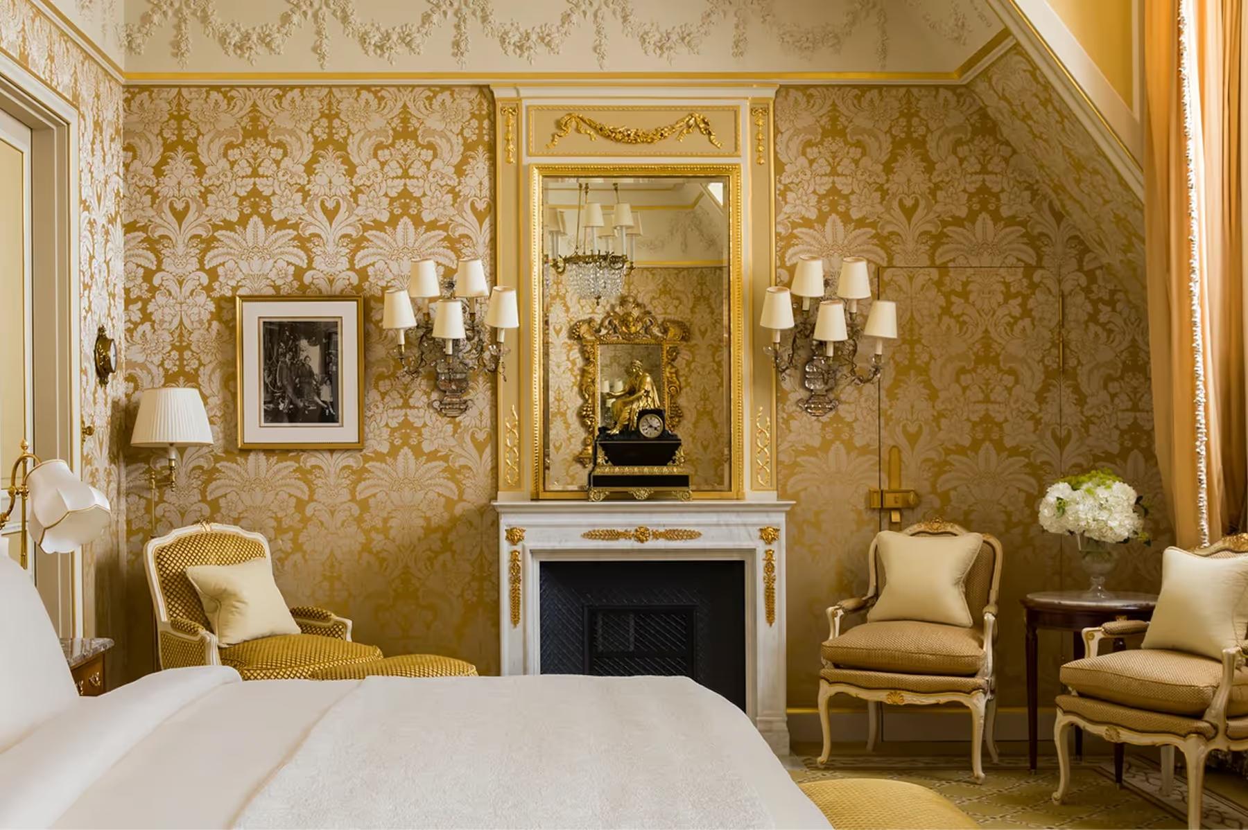 Ritz Paris: a Belle Époque suite with gold damask walls, cream bedding, fireplace mantel, and gilt-framed mirror