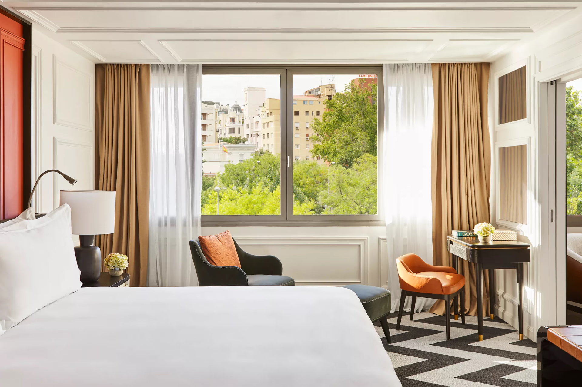 Rosewood Villa Magna: a bedroom with window seating, warm gold curtains, and views of green rooftop gardens