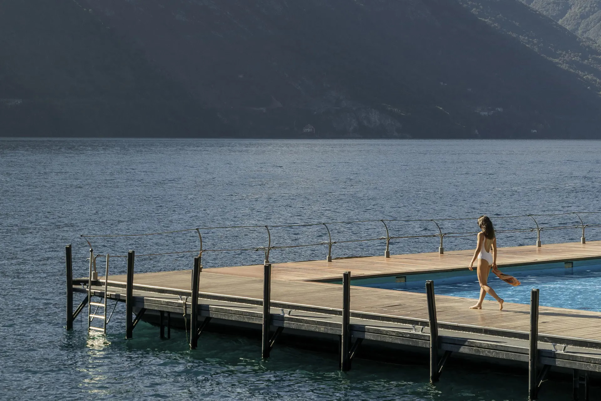 Grand Hotel Tremezzo: woman walking on wooden platform pool deck over sparkling blue water