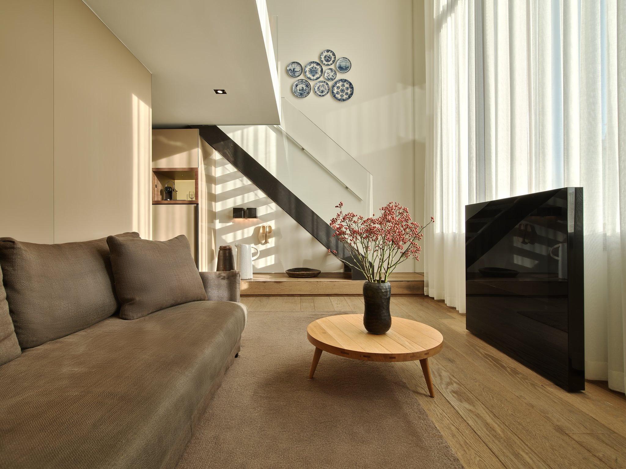 Light-filled loft space with staircase, wood flooring, and living area with greenery