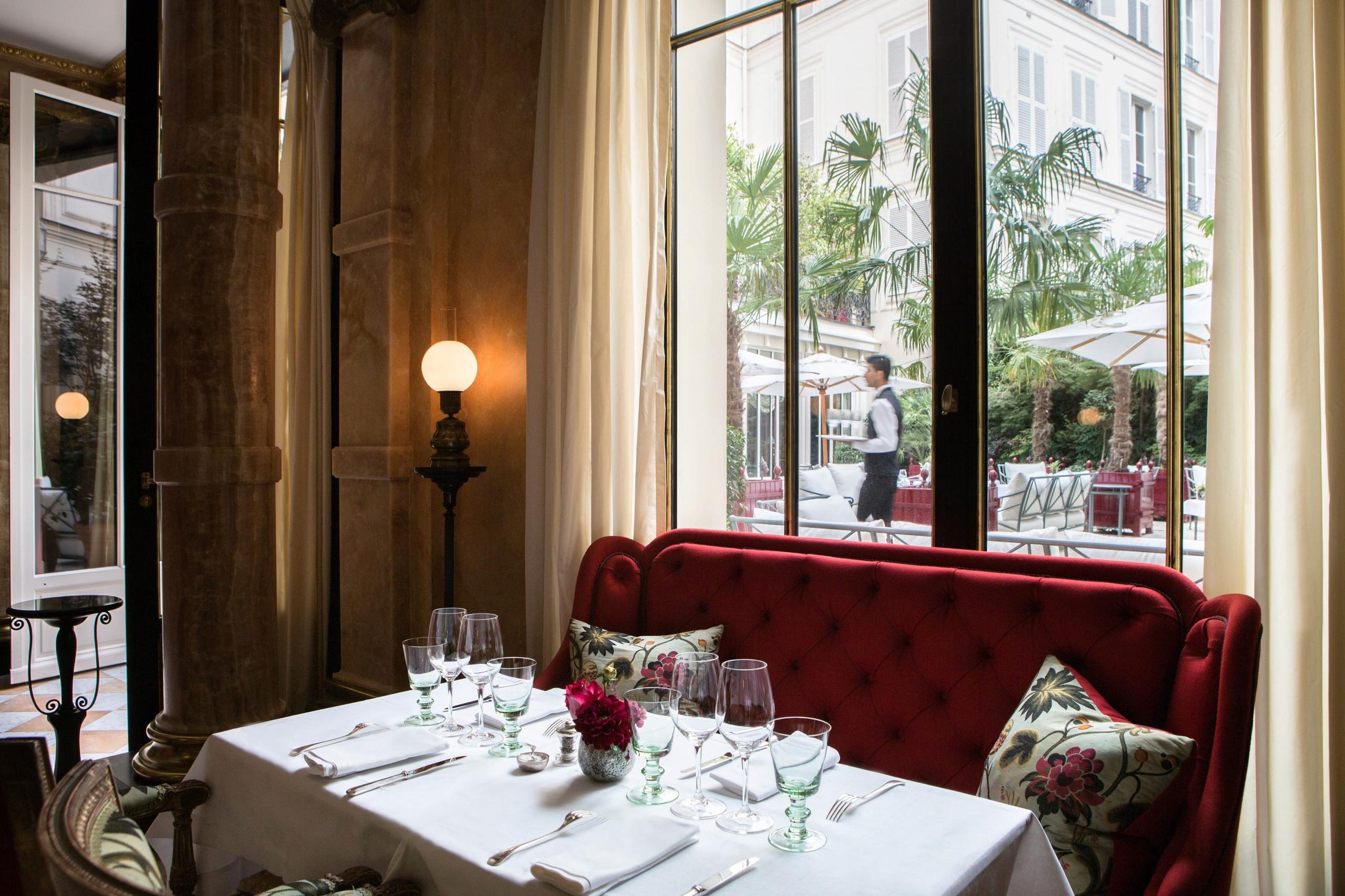 La Réserve Paris: a restaurant window table with cream drapery and garden views
