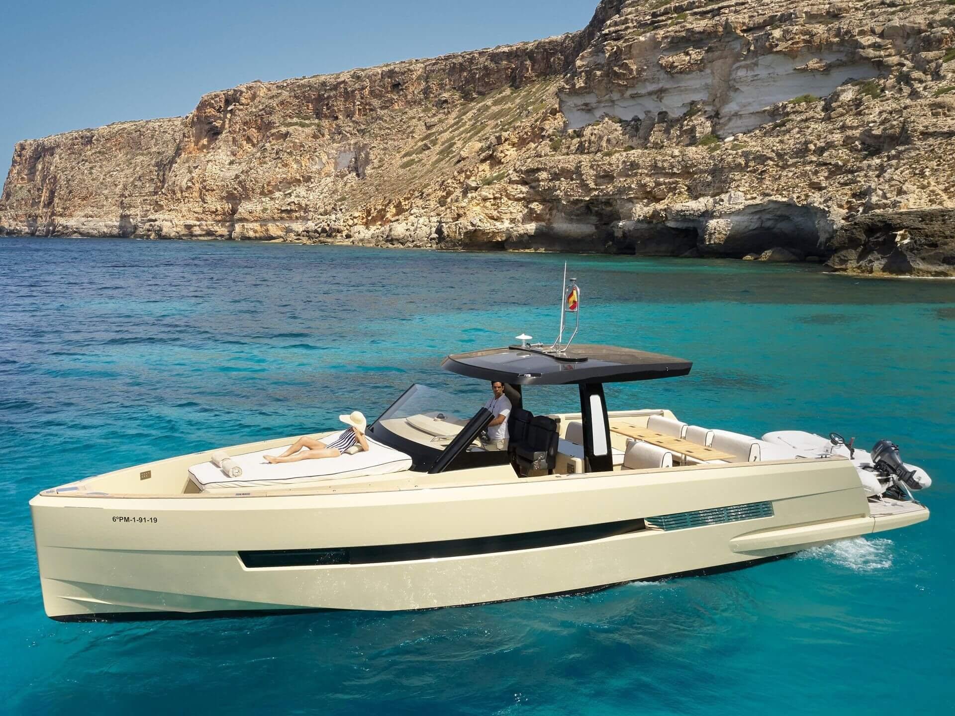 Cap Rocat: a motorboat in crystal turquoise waters framed by limestone cliffs at Cala Blava
