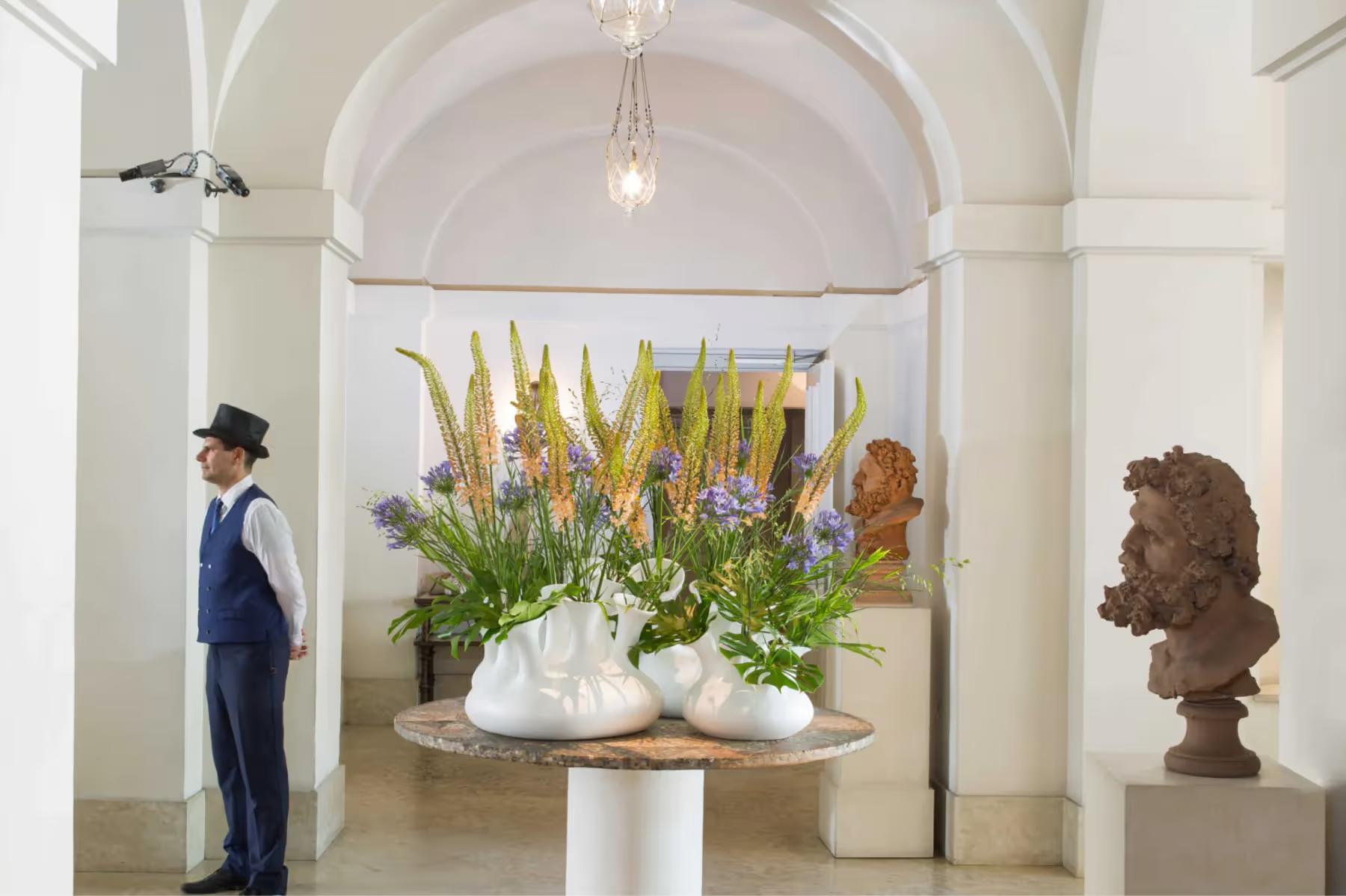 Entrance hall with arched ceiling, tall arrangement of yellow and green flowers in pedestal vase