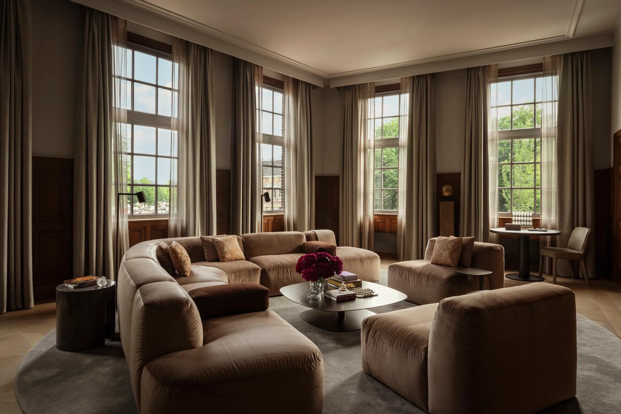 Rosewood Amsterdam: the Herengracht House living room with curved velvet sofas and tall windows over the canal