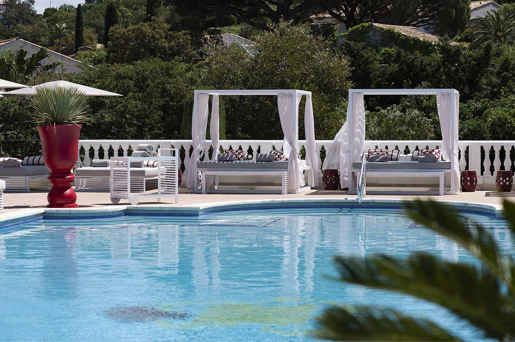 Pool deck with white cabanas and striped loungers overlooking the bay