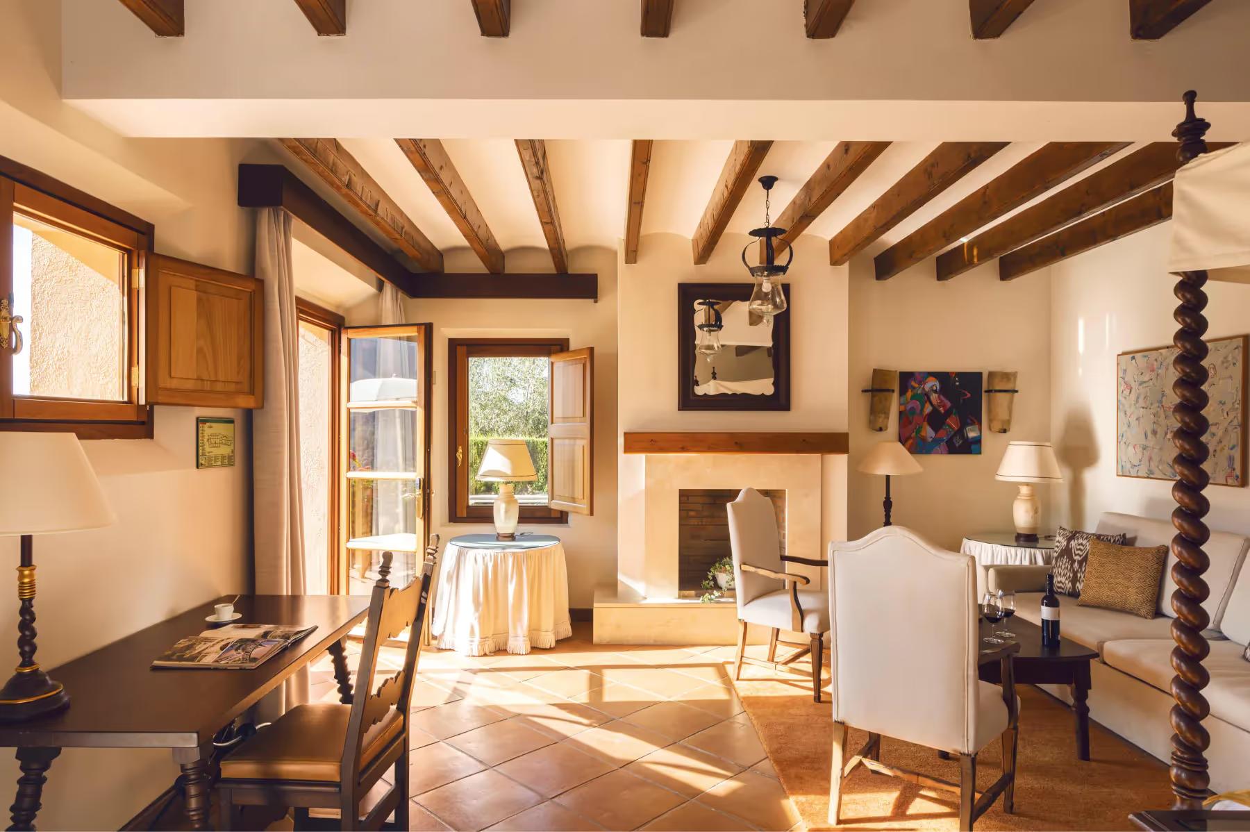 La Residencia: suite interior with exposed beams, wooden doors, and sunlight streaming through open windows