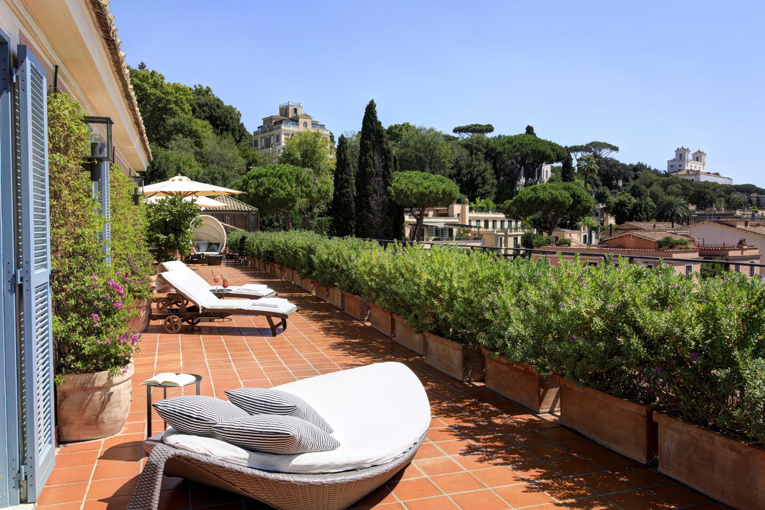 Hotel de Russie: terracotta rooftop seating with loungers and city views at sunset