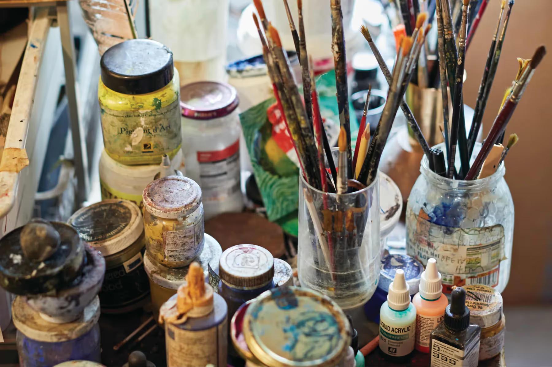 Art studio desk with brushes, jars, and painting supplies for creative work