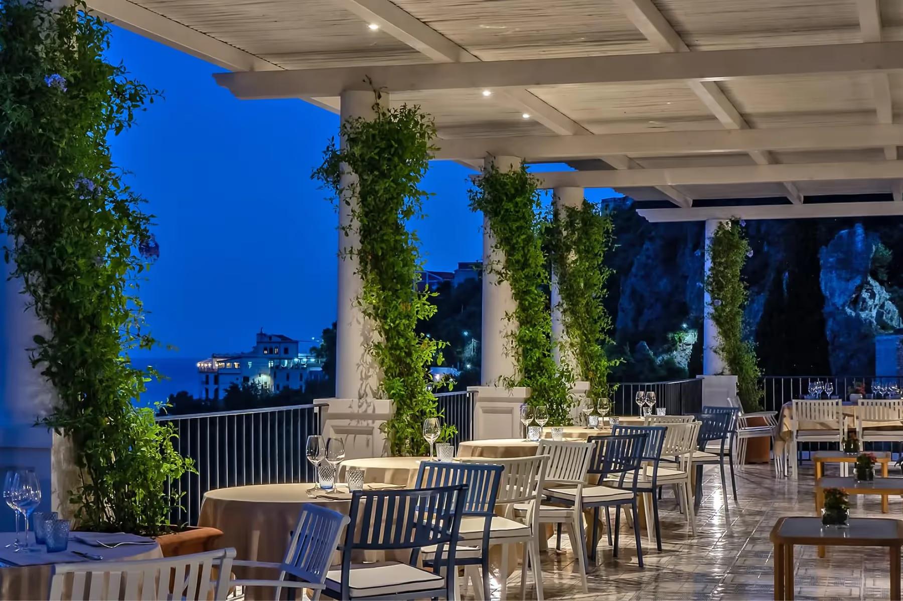 Borgo Santandrea: contemporary covered dining area at night with ivy pillars and Mediterranean seascape
