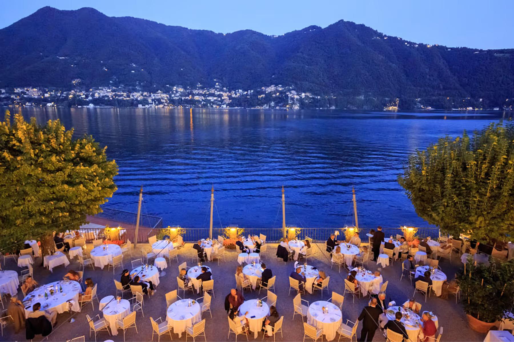 Waterfront dining pavilion at dusk with small wooden boats moored below