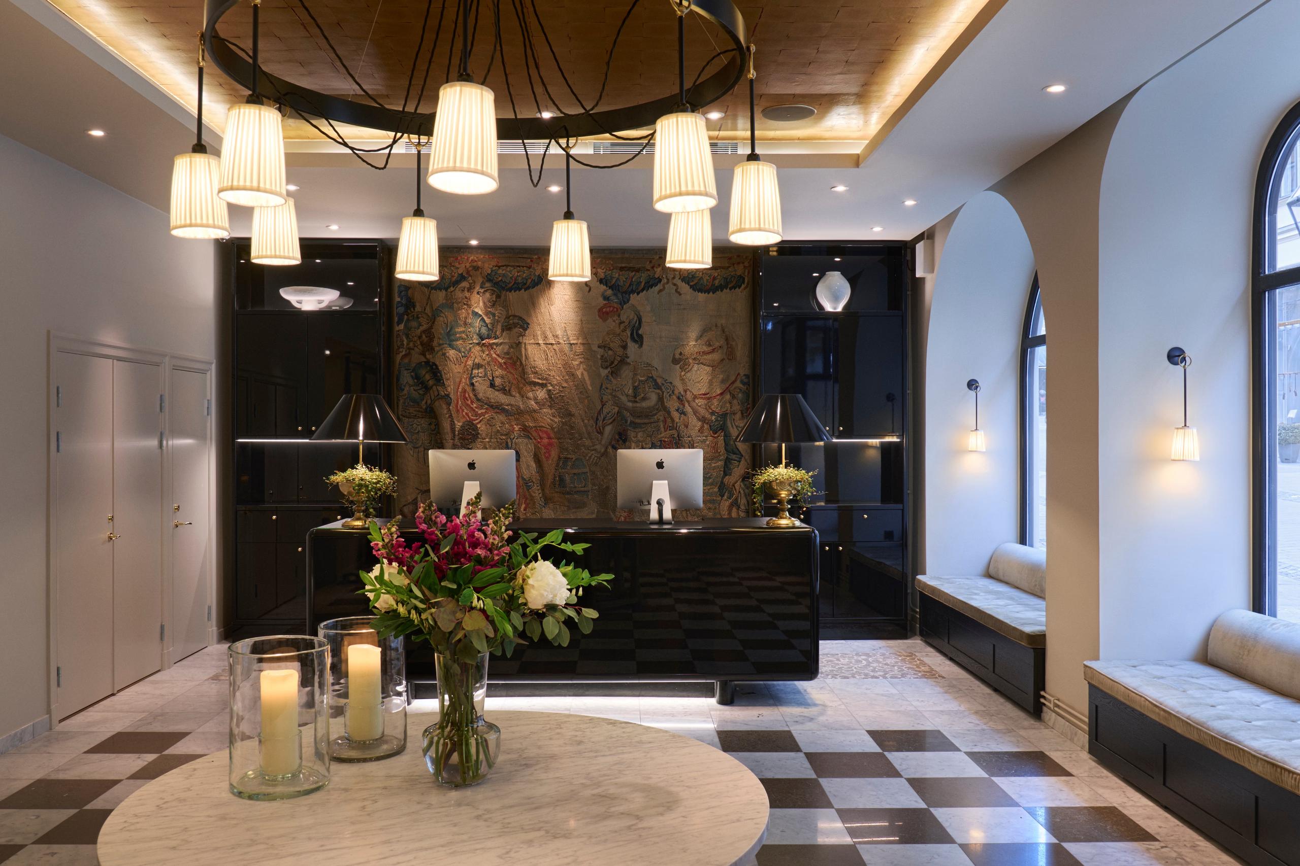 Light-filled lobby with dark accent wall, brass fixtures, and geometric floor pattern