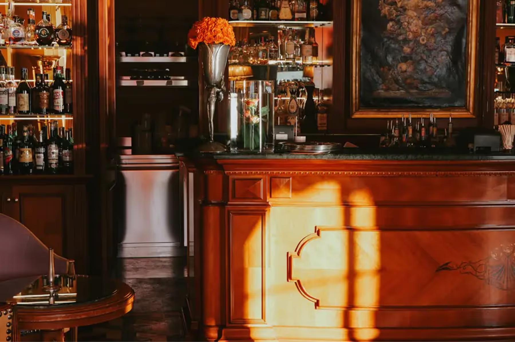 Bar area with wood cabinetry and shelves of bottles in warm light