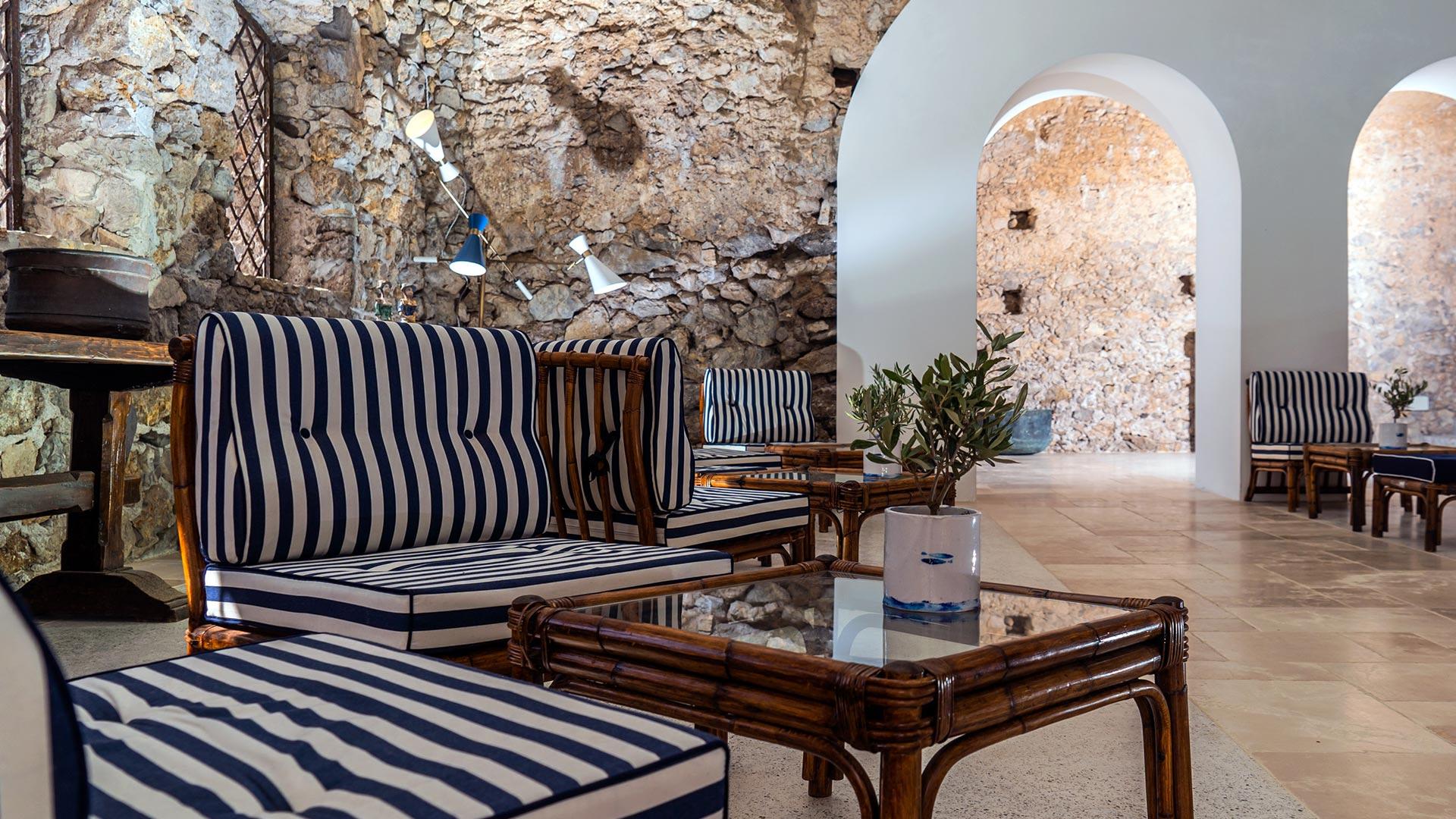 Borgo Santandrea: lounge area with striped sofa, black coffee table, stone walls, and barrel vault ceiling