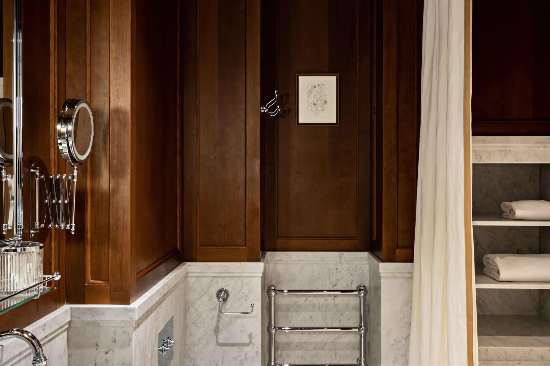 Hôtel Balzac: a marble bathroom with dark wood paneling and a modern circular mirror