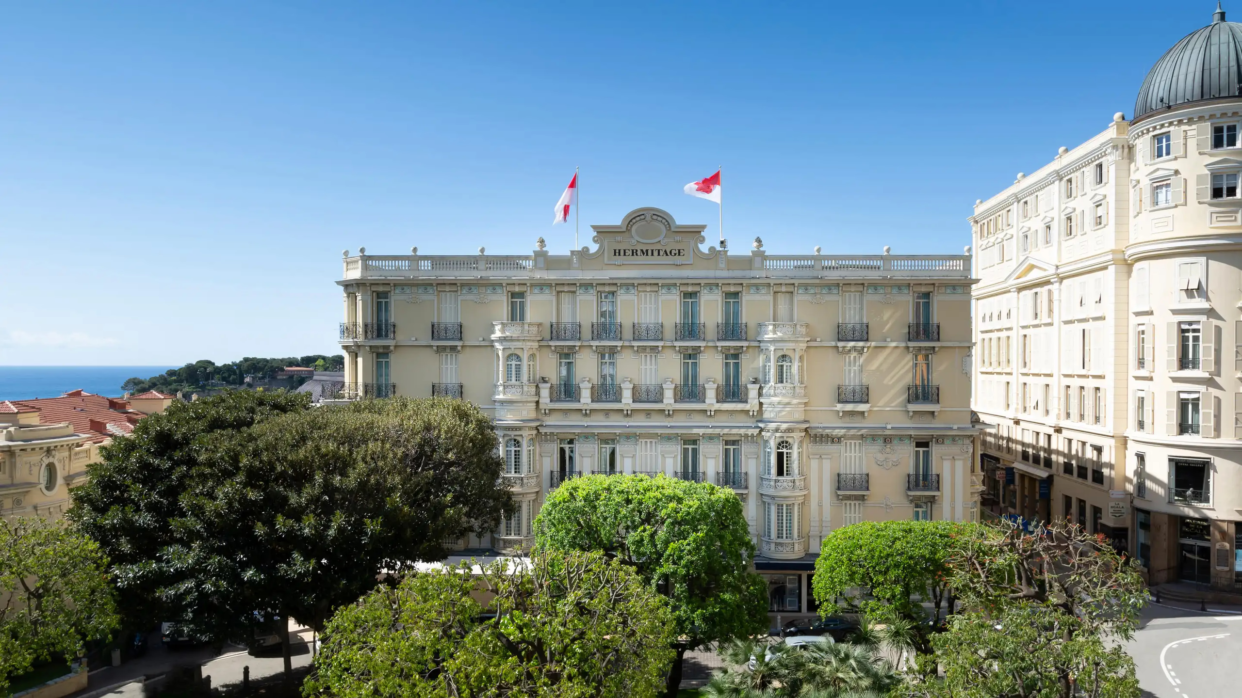 Pale stone palace building with French flags and formal public square below