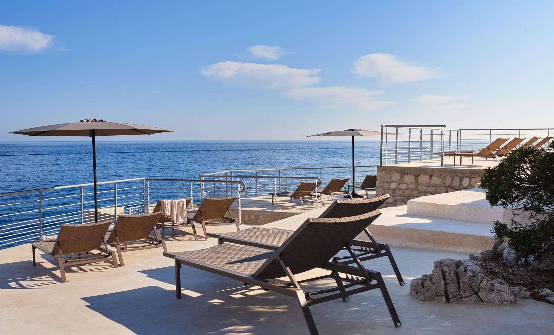 Les Roches Blanches: a poolside lounge area with sun loungers and umbrellas overlooking the Mediterranean Sea
