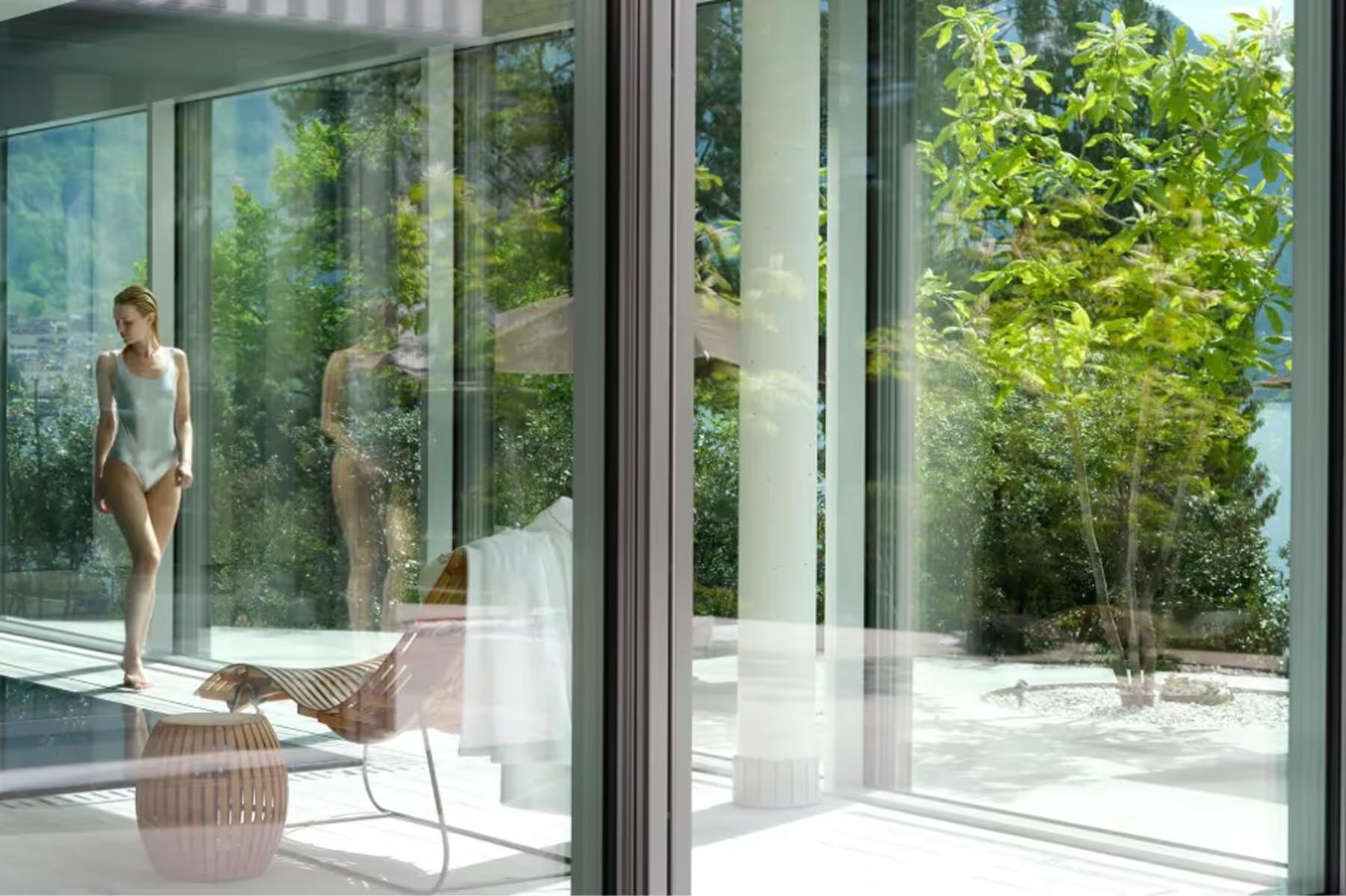 Chenot Palace Weggis: indoor spa pool area with water view, woman in spa dress on white lounger by glass wall