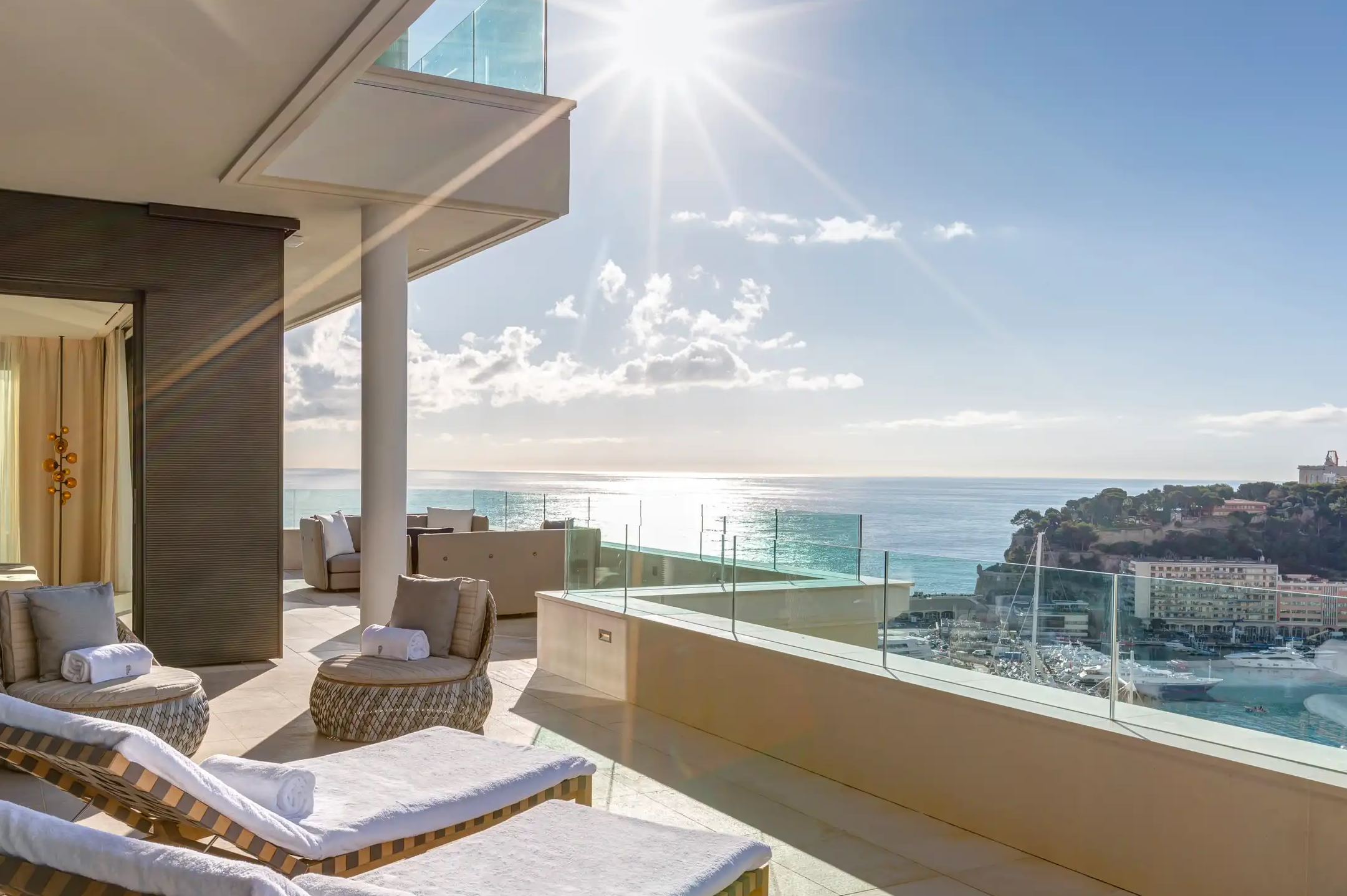 Suite bedroom with white bedding and floor-to-ceiling balcony overlooking sea
