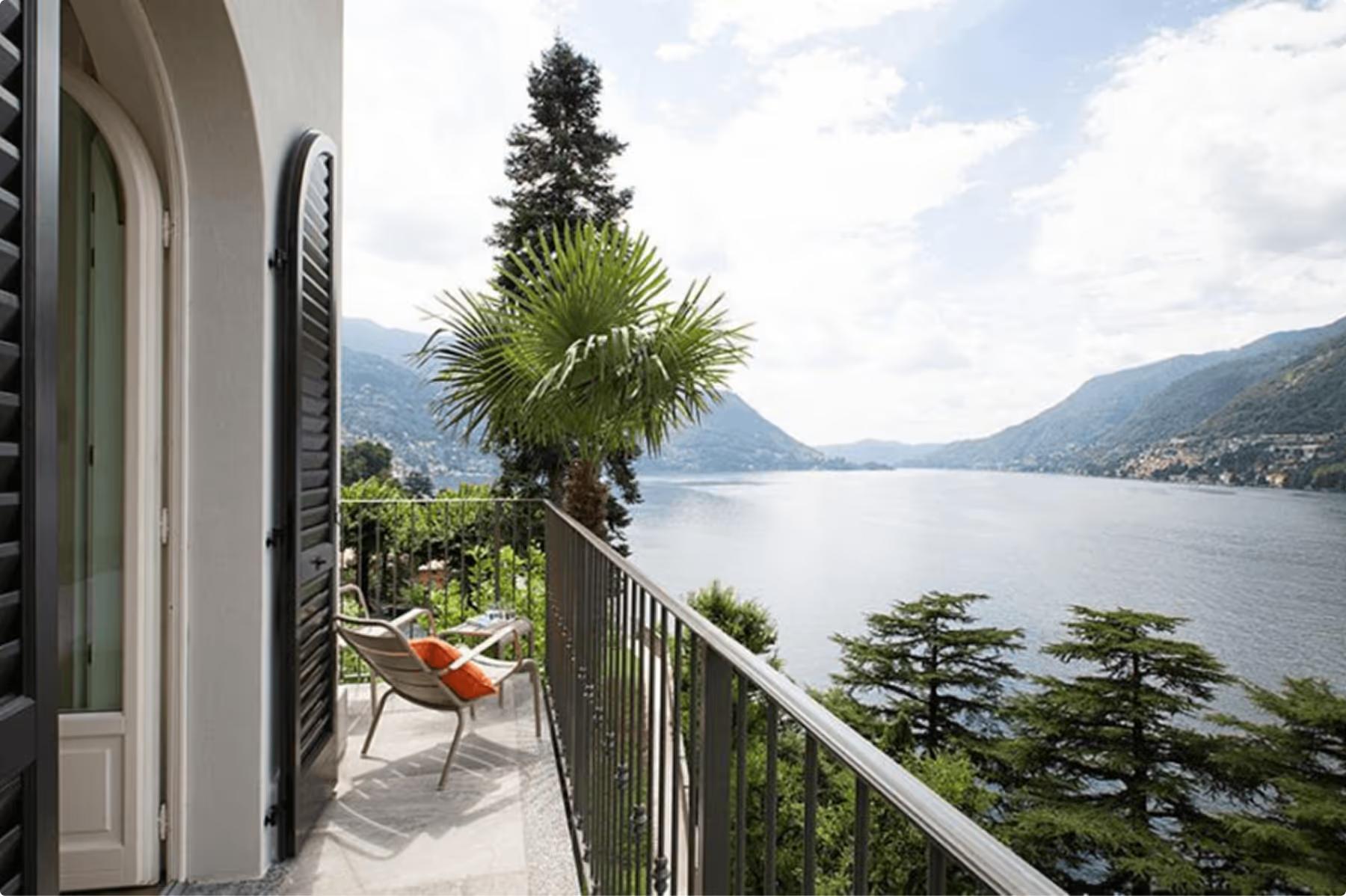 Terrace with shade tree and lounge chairs overlooking mountains and lake