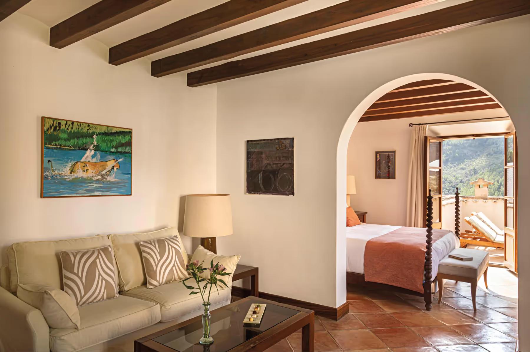 Suite living room with arched stone doorway, upholstered seating, and view to landscape beyond