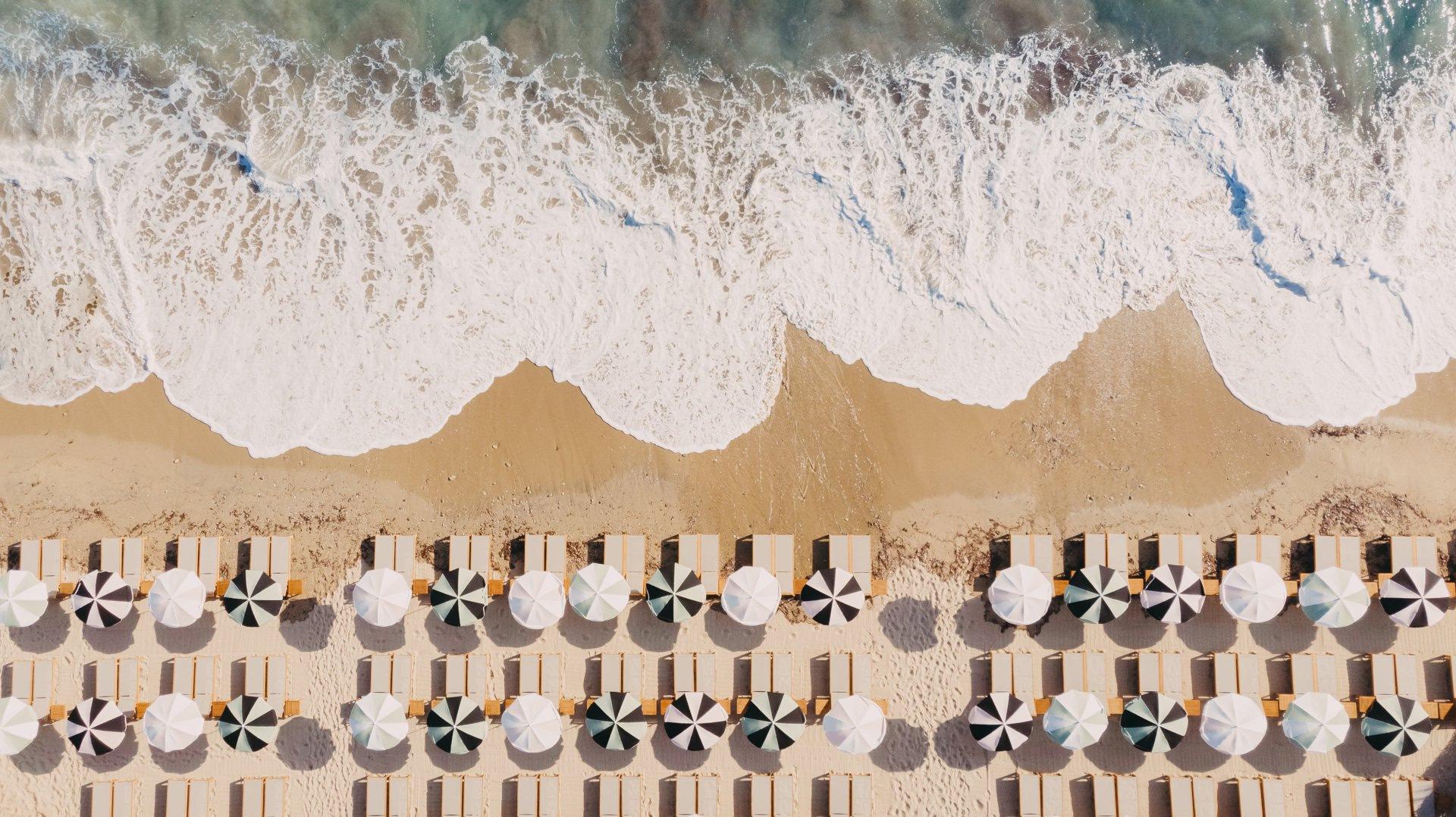 Aerial view of beach loungers arranged in rows above Mediterranean waves